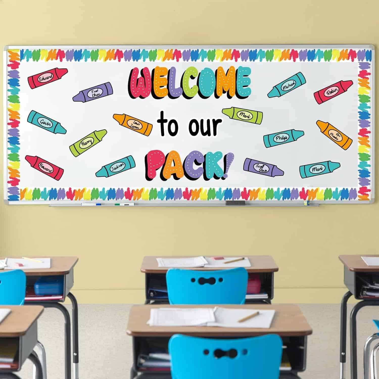 A classroom with blue chairs and desks faces a colorful bulletin board that reads "Welcome to our Pack!" with crayon illustrations and a rainbow border.