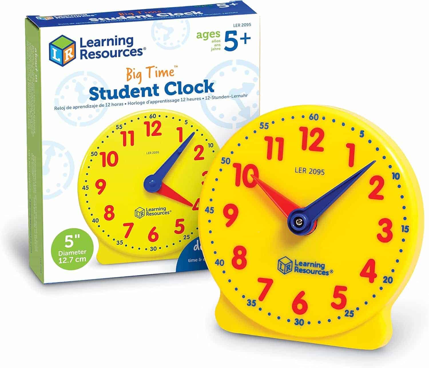 A yellow plastic student clock with movable red and blue hands is shown next to its packaging, labeled for ages 5+ and measuring 5 inches in diameter.