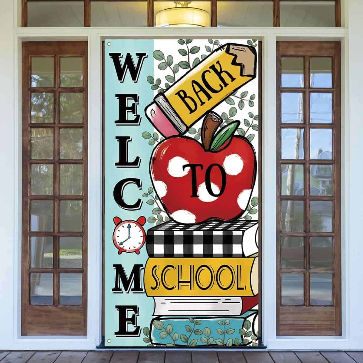 Colorful banner with an apple, books, pencil, and alarm clock reads "Welcome Back to School" and hangs on a door with glass panels.
