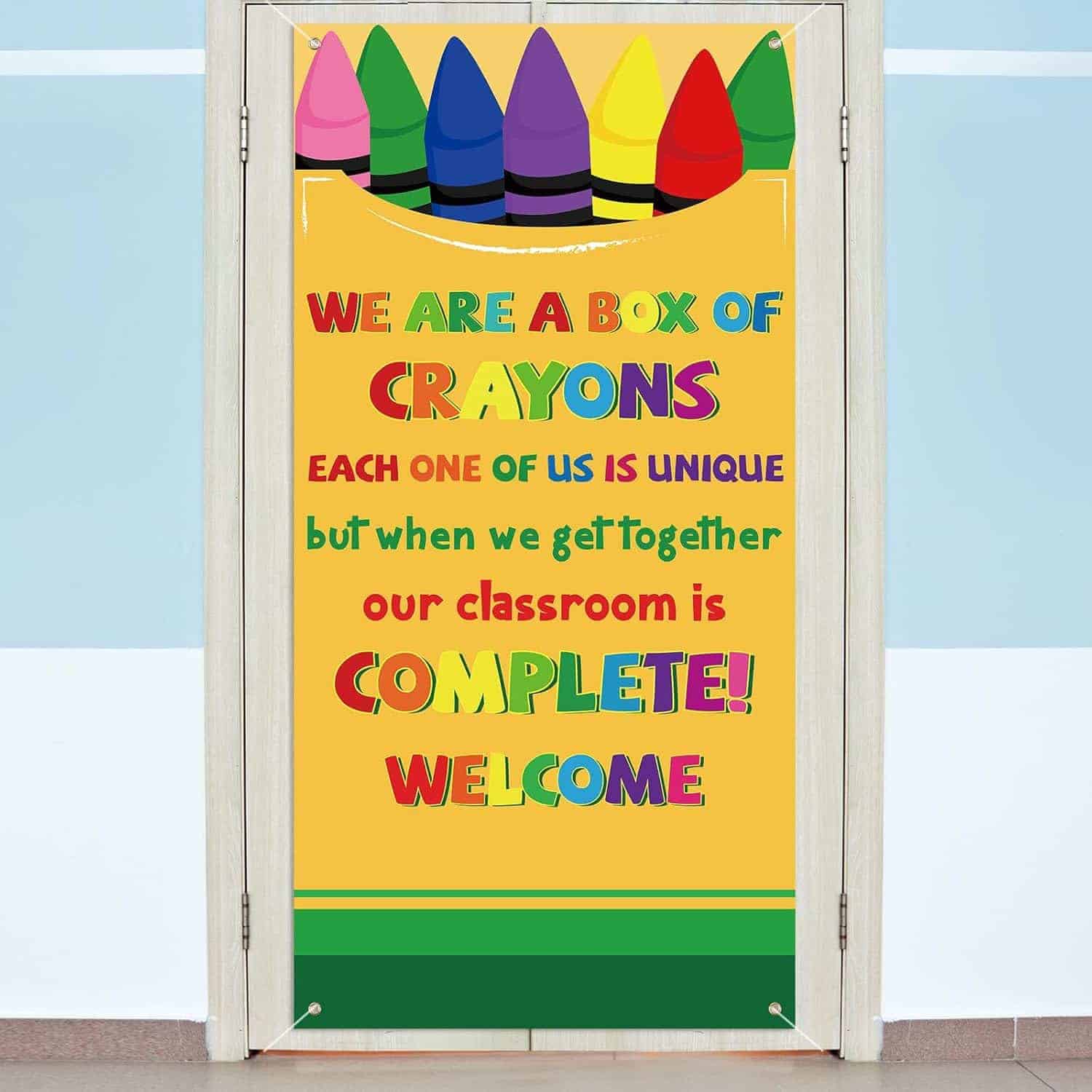 A door decorated with a poster showing large crayons and the message: "We are a box of crayons. Each one of us is unique but when we get together our classroom is complete! Welcome.