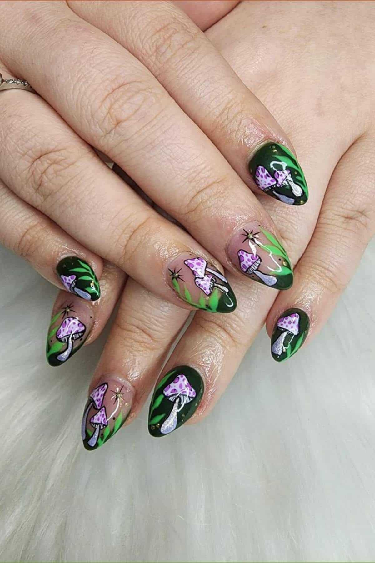 Hands with long, pointed nails painted with a green base and detailed designs of purple and white mushrooms, leafy accents, and small sparkles.