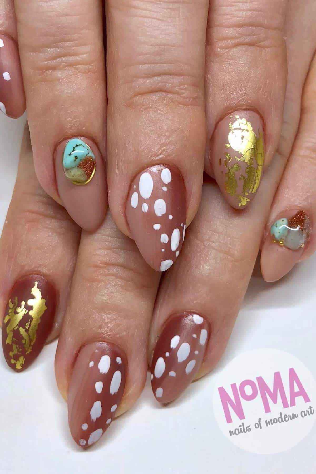 Hands with almond-shaped nails featuring nude polish, white polka dots, gold foil accents, and turquoise marble designs. "NoMA nails of modern art" logo in lower corner.