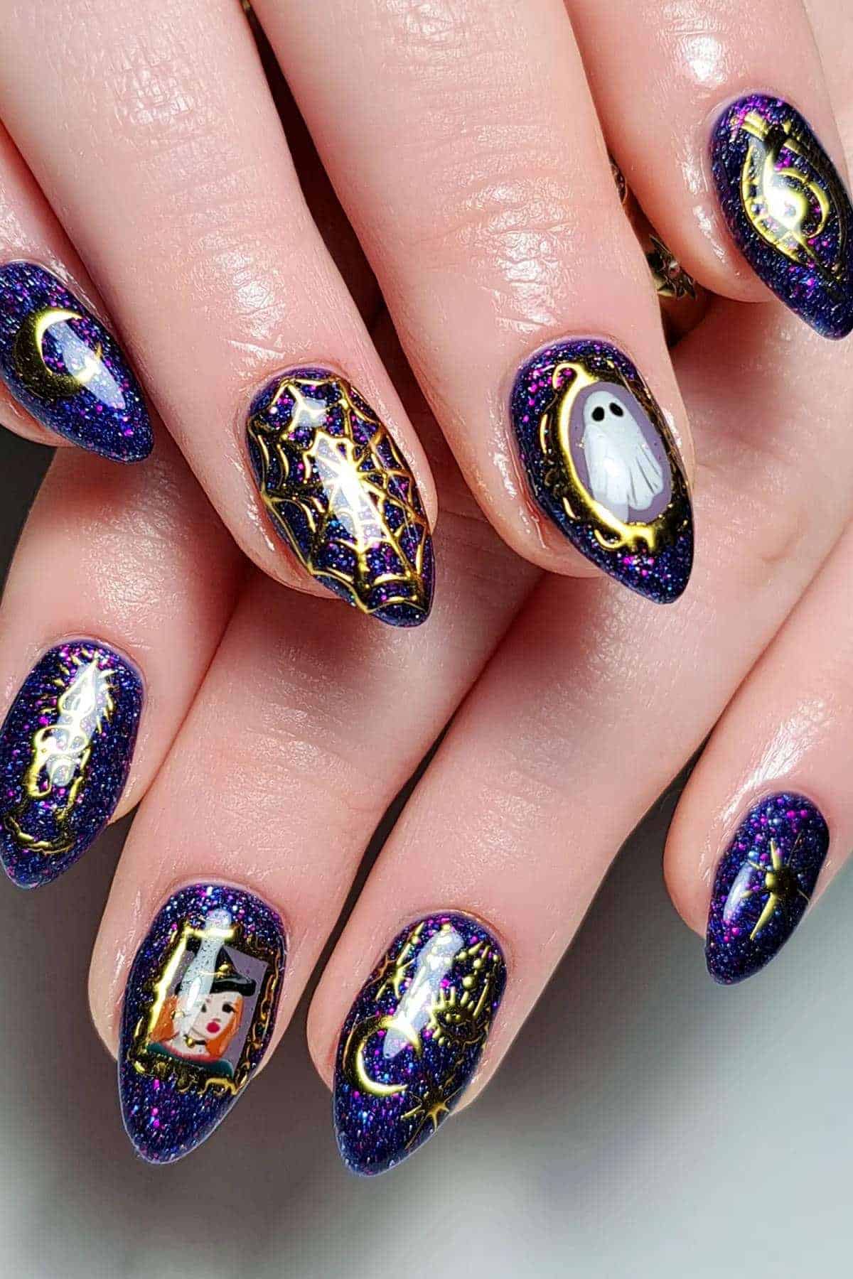 Close-up of hands with pointed nails painted dark purple and decorated with Halloween-themed designs including a ghost, spider webs, a cat, and a pumpkin.