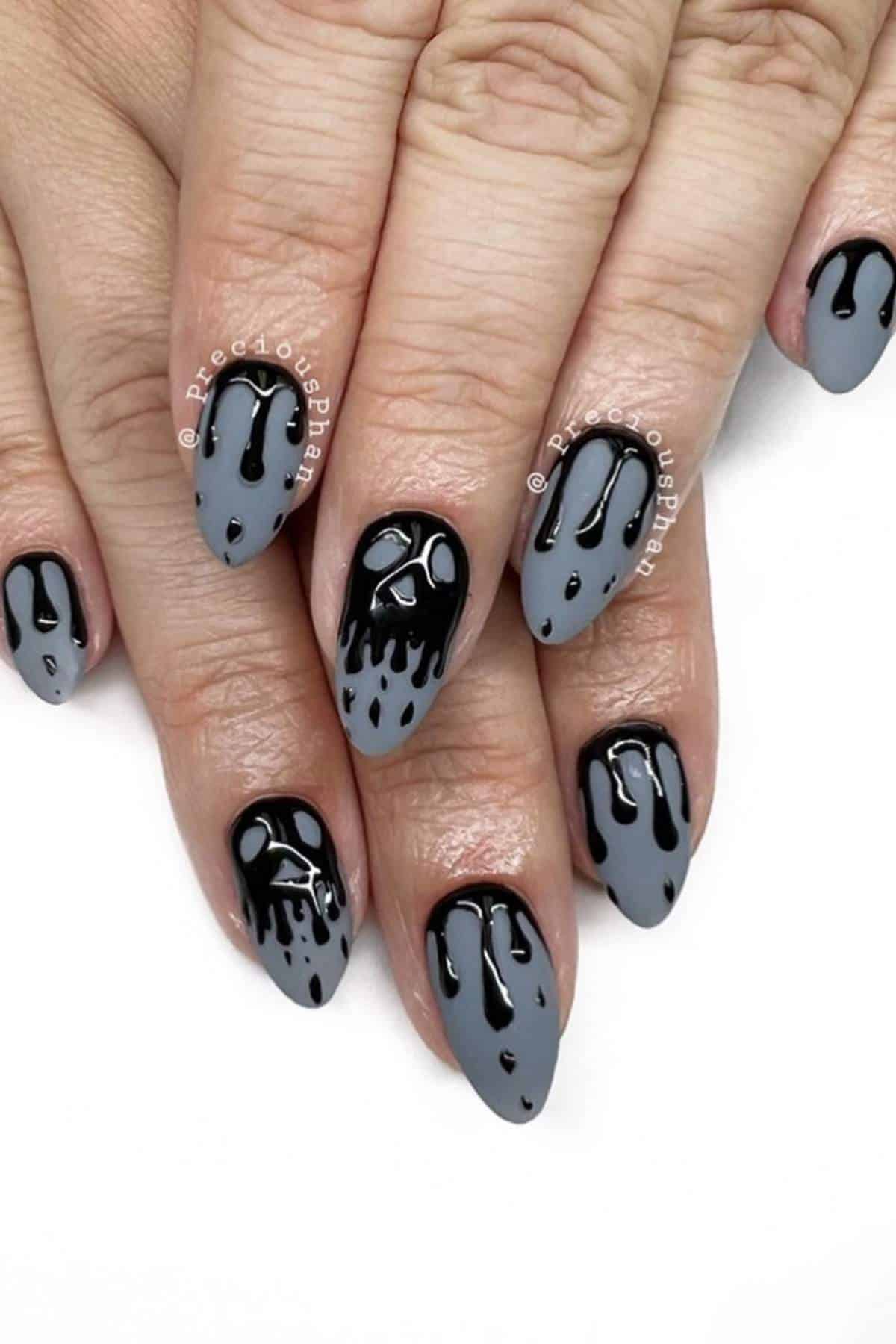 Gray almond-shaped nails with black dripping paint design, featuring one accent nail with a ghost face on the middle finger.