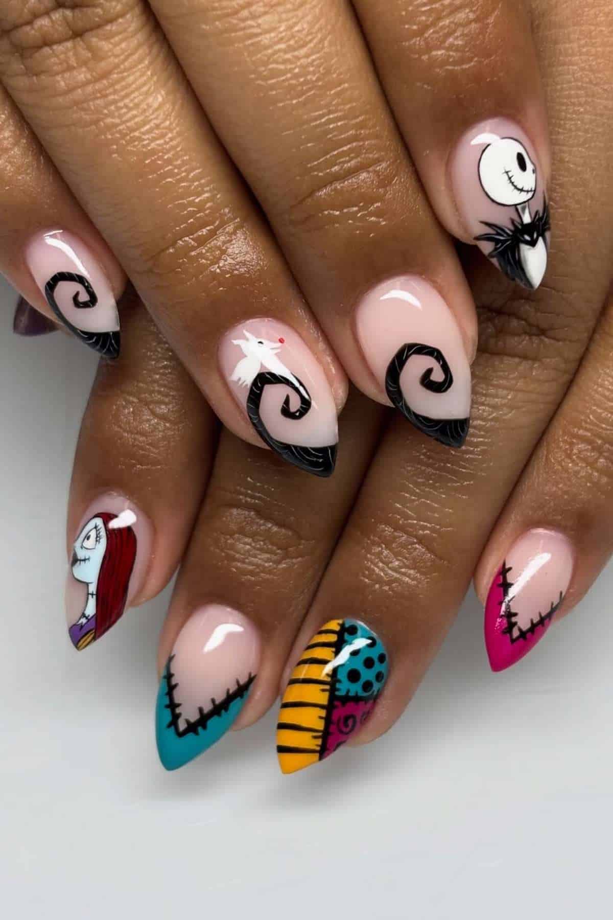 Hands with long, almond-shaped nails featuring "The Nightmare Before Christmas" character art, including Jack Skellington, Sally, and colorful patterns on a nude base.