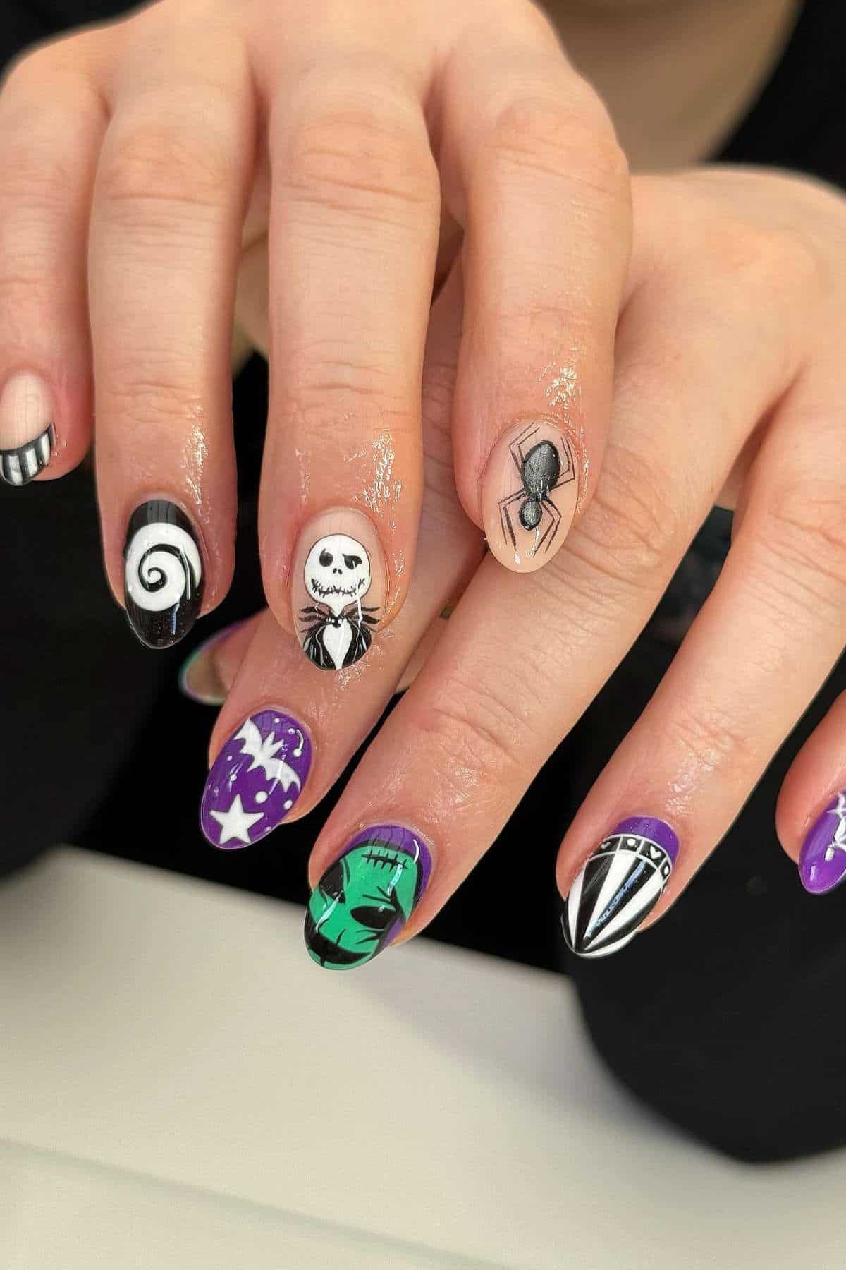 Close-up of hands with Halloween-themed nail art, featuring Jack Skellington, a spider, black and white swirls, green stitches, purple stars, and striped designs.