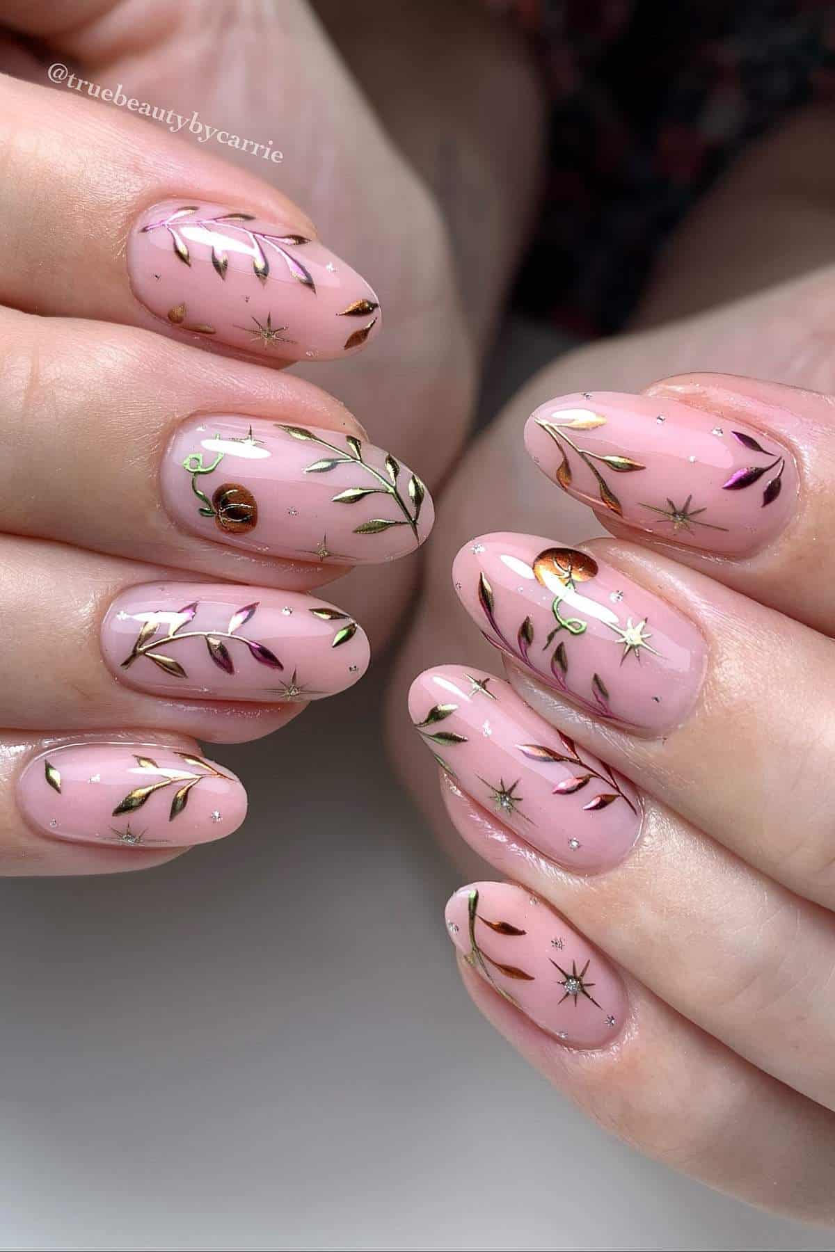 Close-up of hands with almond-shaped, pink polished nails featuring gold leaf and star designs.