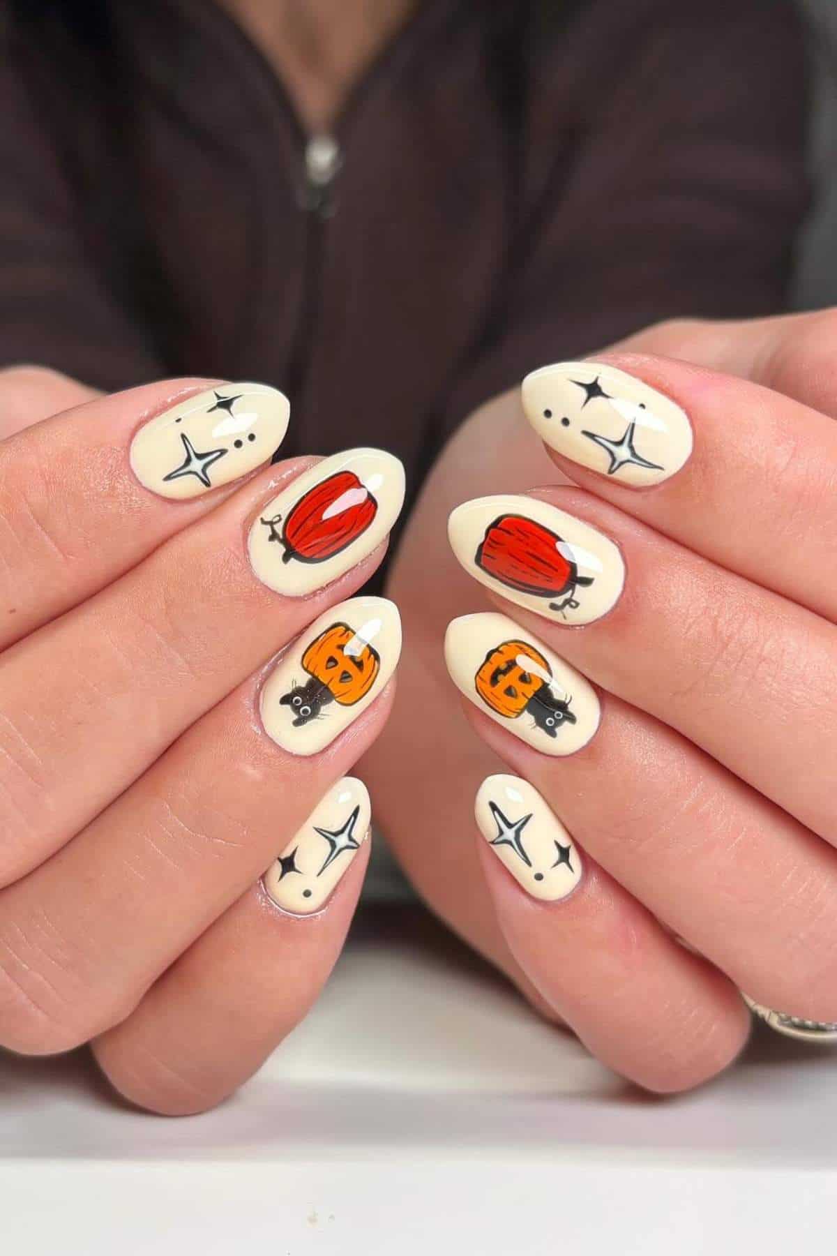 Close-up of hands with almond-shaped nails painted white, featuring hand-drawn pumpkins, jack-o'-lanterns, and black stars.