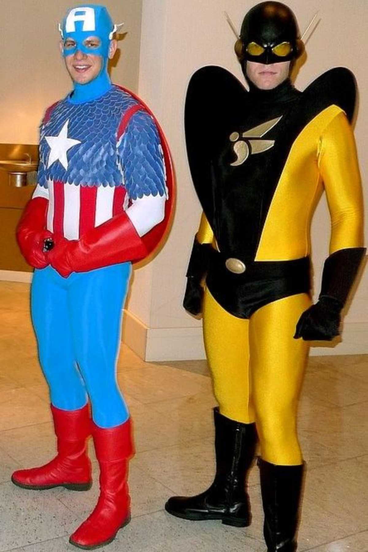 Two people in superhero costumes stand side by side; one dressed as Captain America in red, white, and blue, and the other in a black and yellow suit with a helmet and antennae.