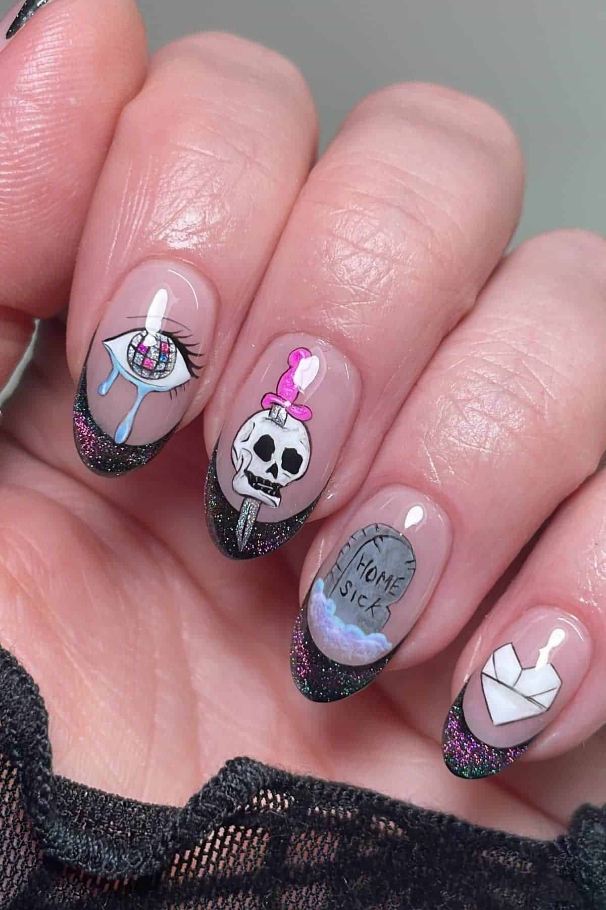 A hand with long nails featuring black glitter tips and detailed nail art: an eye with tears, a skull with a candle, a gravestone reading “homesick,” and an envelope with a wax seal.