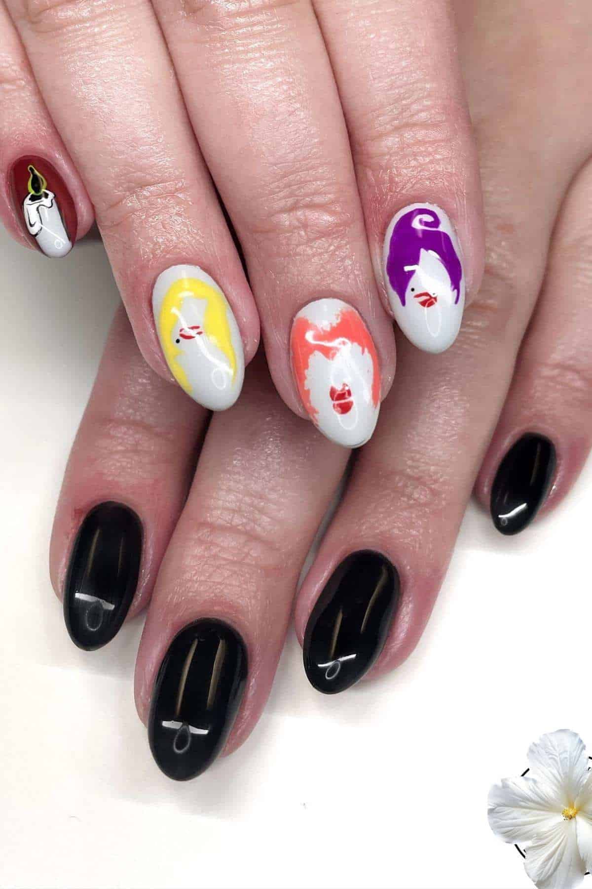 A hand with nails painted black on one hand and white with colorful abstract faces on the other. A white flower is in the bottom right corner.