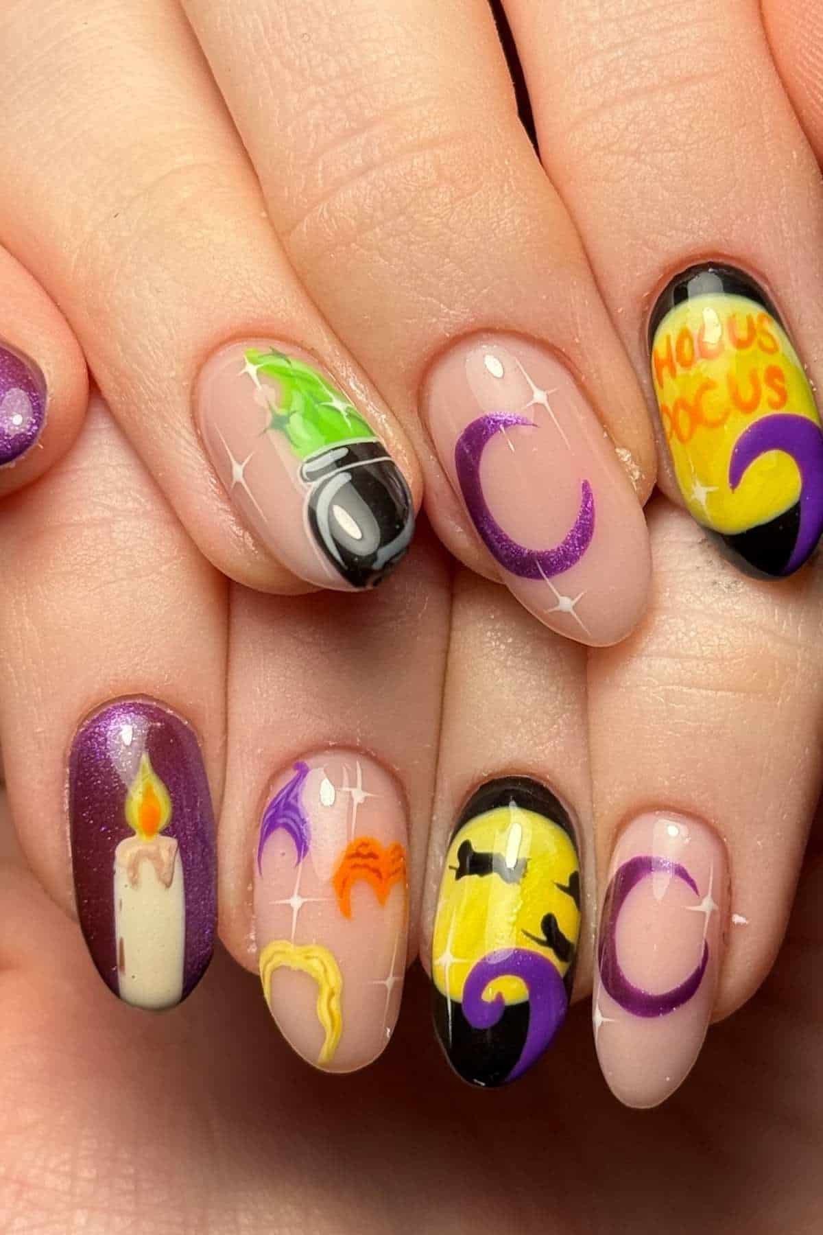 Close-up of hands with Halloween-themed nail art, featuring a candle, witch motifs, purple moons, and “Hocus Pocus” text in yellow and orange.