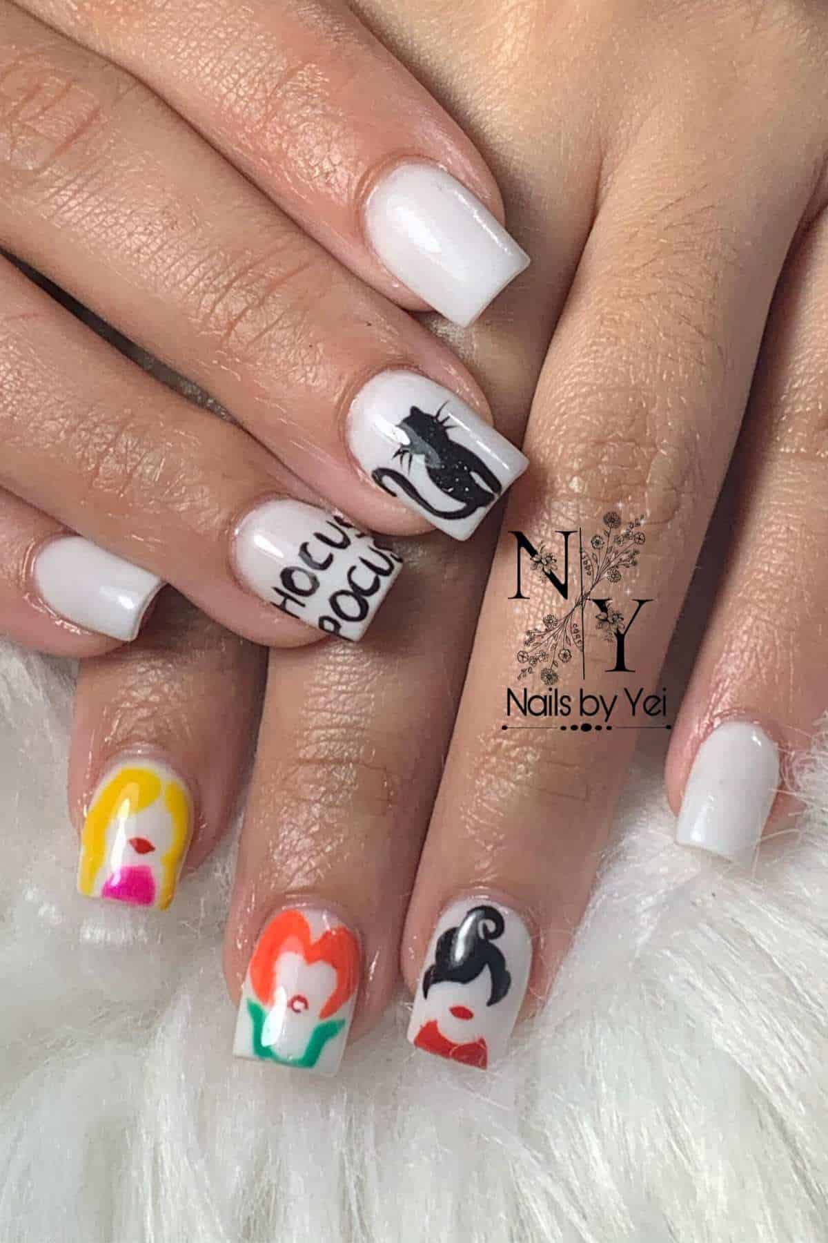 Hands with white square-shaped nails, featuring colorful floral designs and black graphic art accent nails, resting on a fluffy surface.