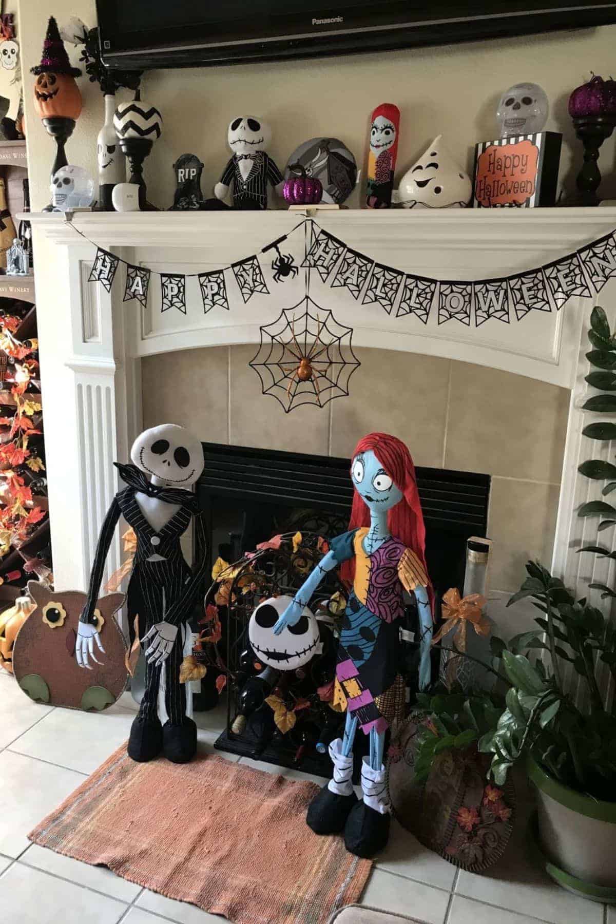 Halloween-themed living room with “The Nightmare Before Christmas” dolls, pumpkin decorations, Halloween banner, and autumn accents arranged around a fireplace.