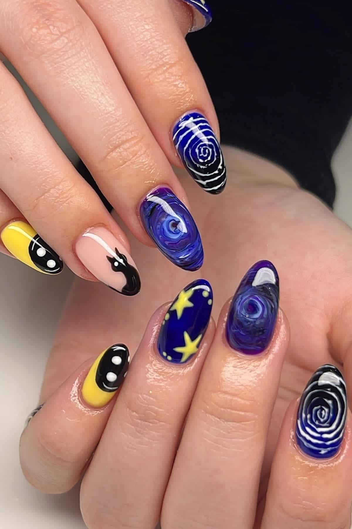 A close-up of hands with long, oval nails featuring cosmic, star, swirl, yellow, and black abstract nail art designs on each fingernail.
