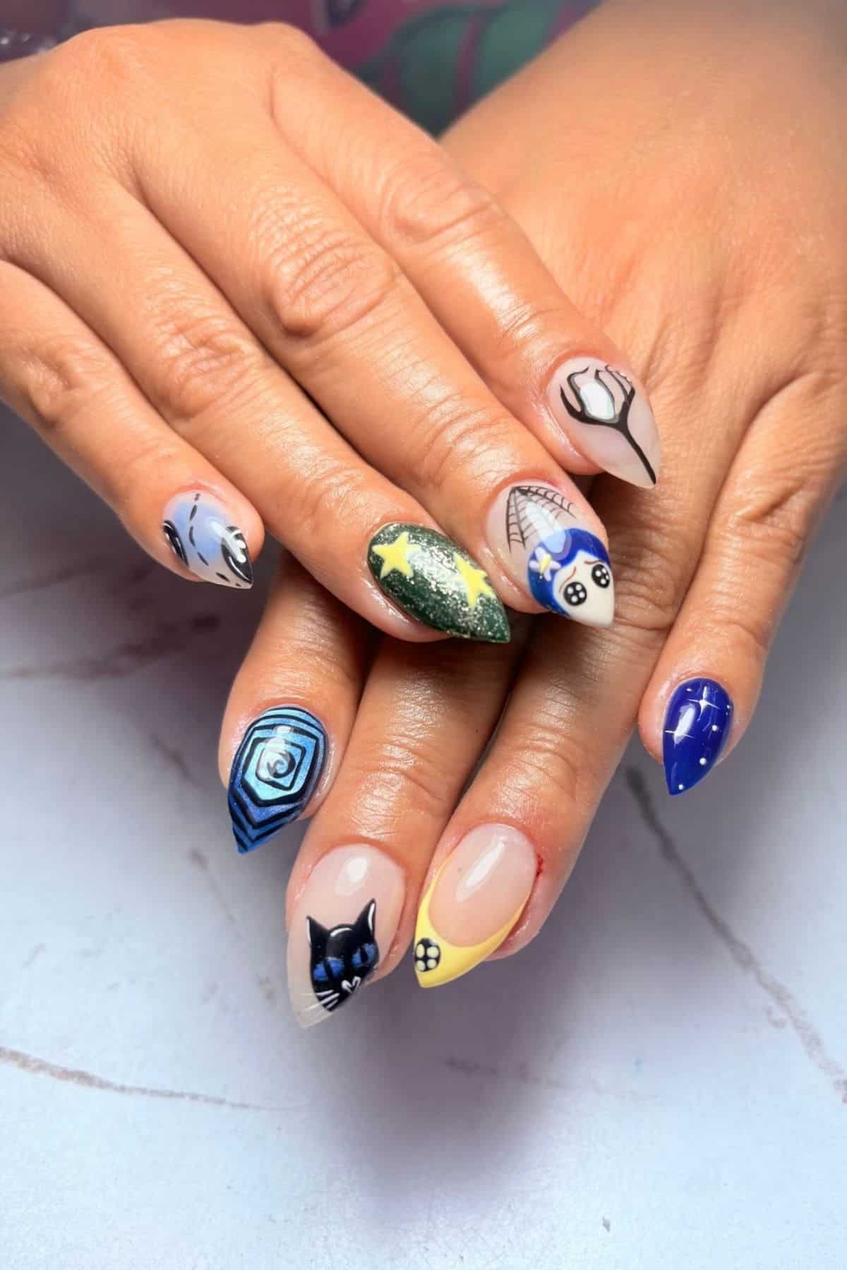 Hands with long, pointed nails featuring detailed Coraline-themed nail art on a light surface.