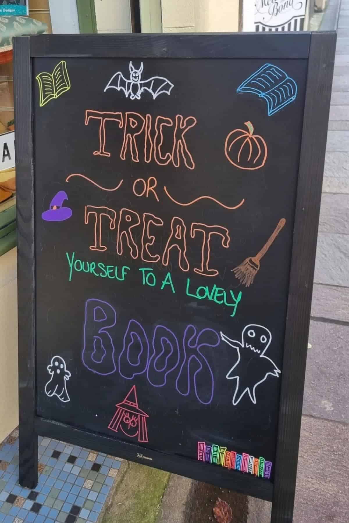 Chalkboard sign with Halloween drawings and the message: “Trick or treat yourself to a lovely book.”.