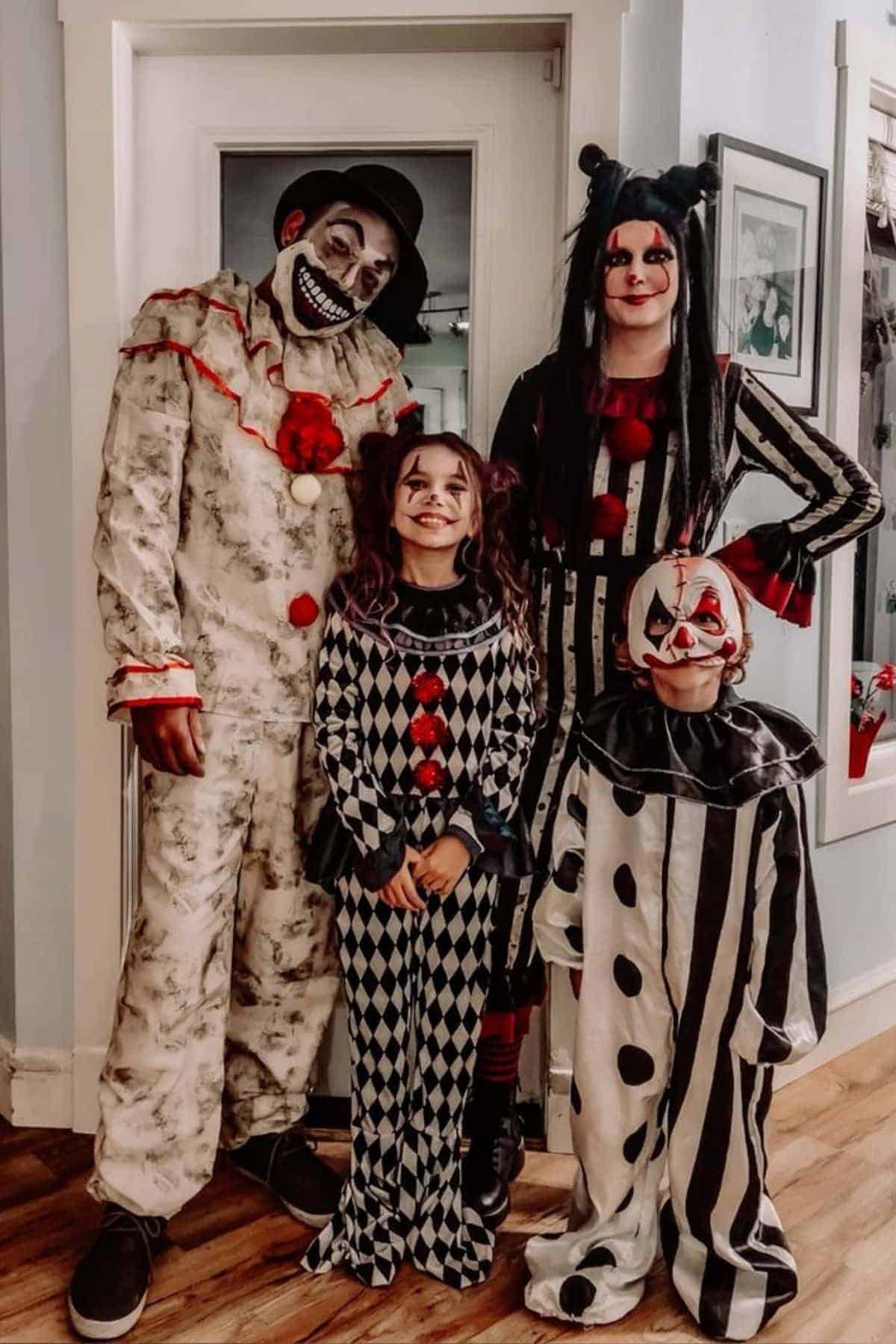 Four people in black, white, and red clown costumes pose together indoors, standing in front of a white door.