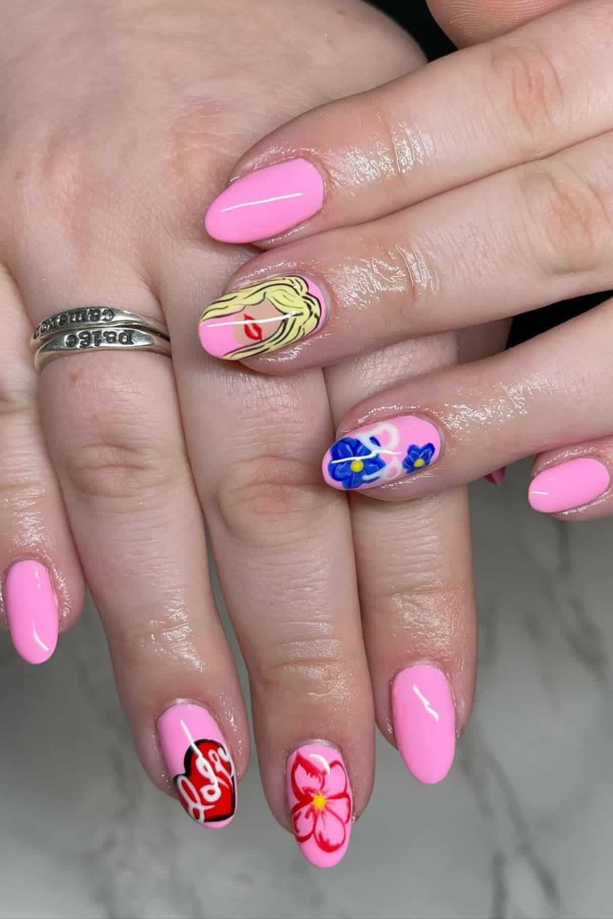 Hands with pink manicured nails featuring various designs including a blonde woman’s face, flowers, and a red heart with the word “Love.”.