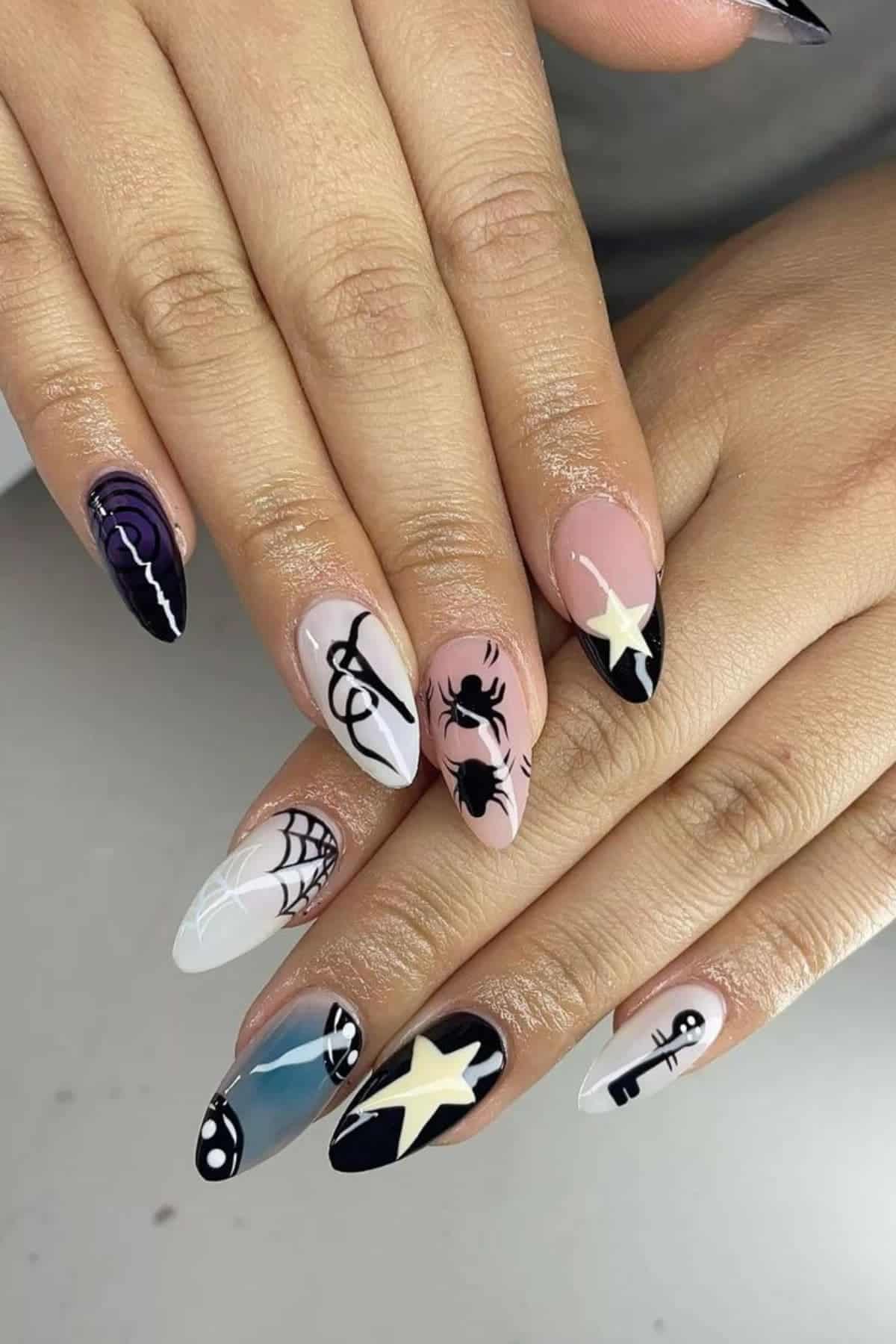 Hands with long almond-shaped nails featuring Halloween-themed designs, including spiders, webs, stars, bones, and abstract patterns in black, white, and purple.