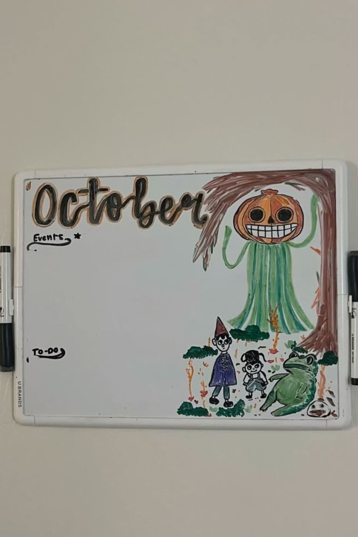 Whiteboard with “October” written at the top, drawings of Halloween-themed characters, and sections for “Events” and “To-Do” lists, both currently blank. Two markers attached to the board.