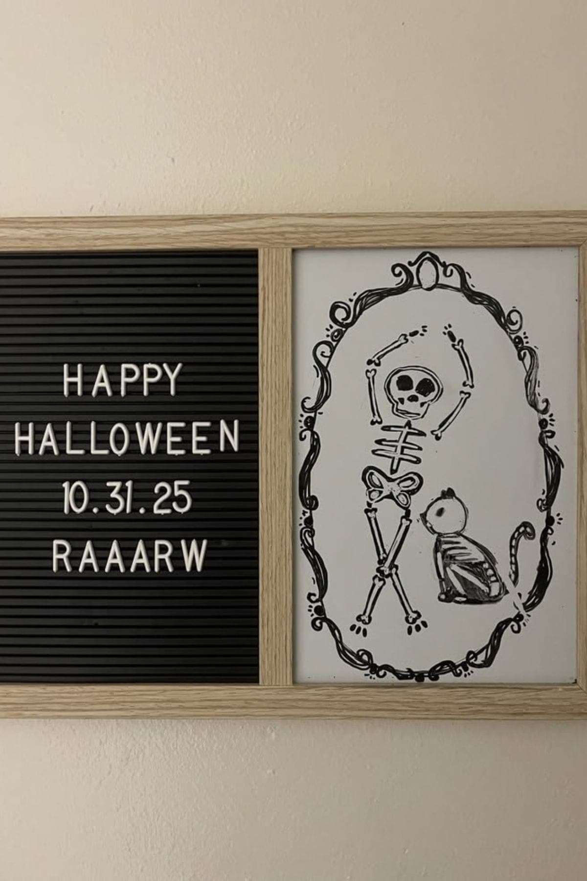 A letter board says “Happy Halloween 10.31.25 RAARW” next to a drawing of a skeleton with arms up and a small animal skeleton inside a decorative frame.