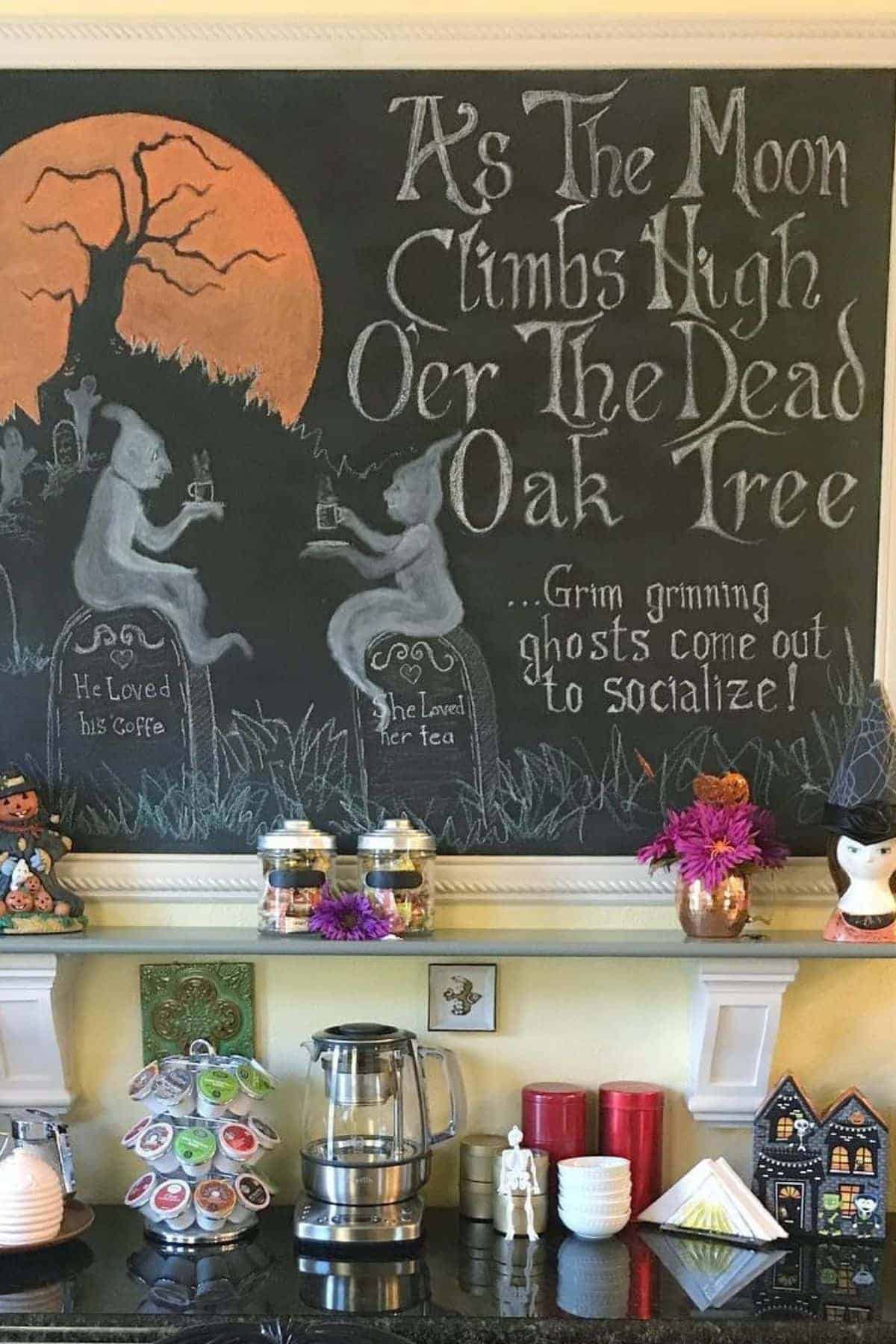A chalkboard features ghosts at tables with drinks, a large orange moon, gravestones, and the words “As The Moon Climbs High O’er The Dead Oak Tree… Grim grinning ghosts come out to socialize!”.