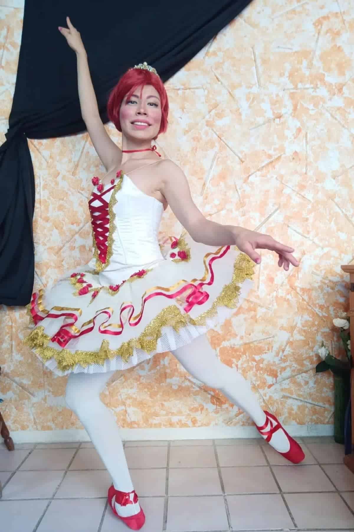 Person in a white and red ballet costume poses in a dance position indoors, with one arm raised and a leg extended.