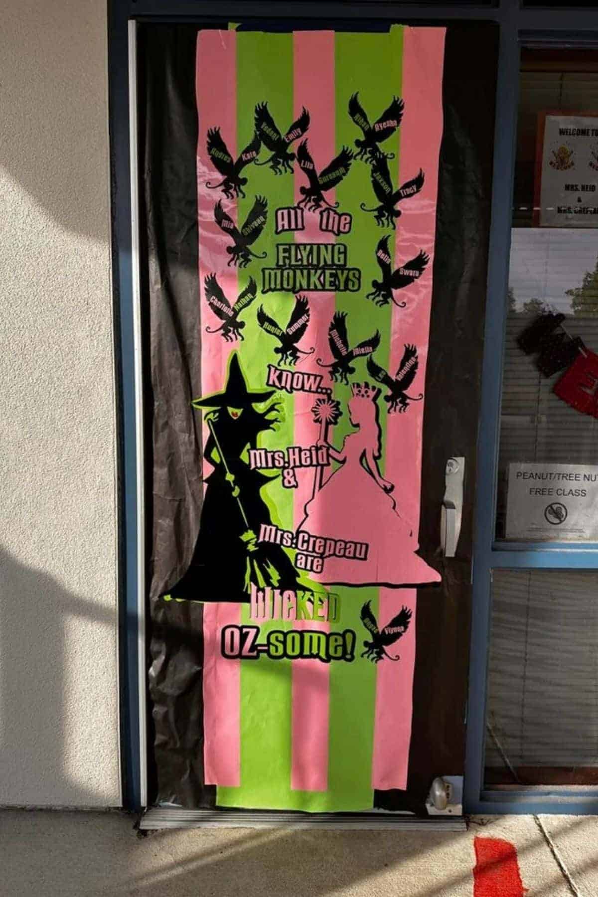 Classroom door decorated with pink and green stripes, flying monkeys, a witch silhouette, and text referencing “The Wizard of Oz” and teachers Mrs. Heldt and Mrs. Crepeau.