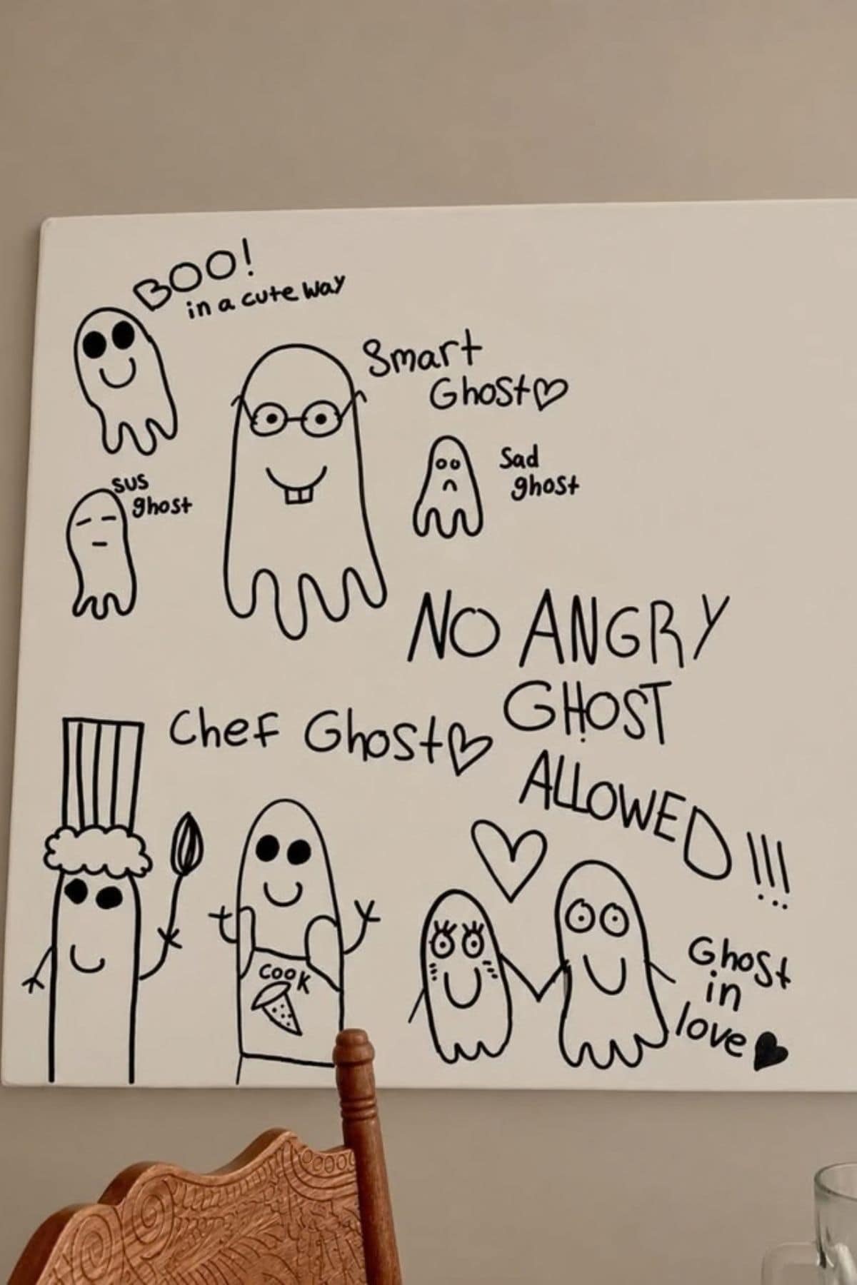 Whiteboard with cartoon ghosts labeled “sus ghost,” “smart ghost,” “sad ghost,” “chef ghost,” and “ghost in love”; text says “No angry ghost allowed!” and “Boo! in a cute way.”.
