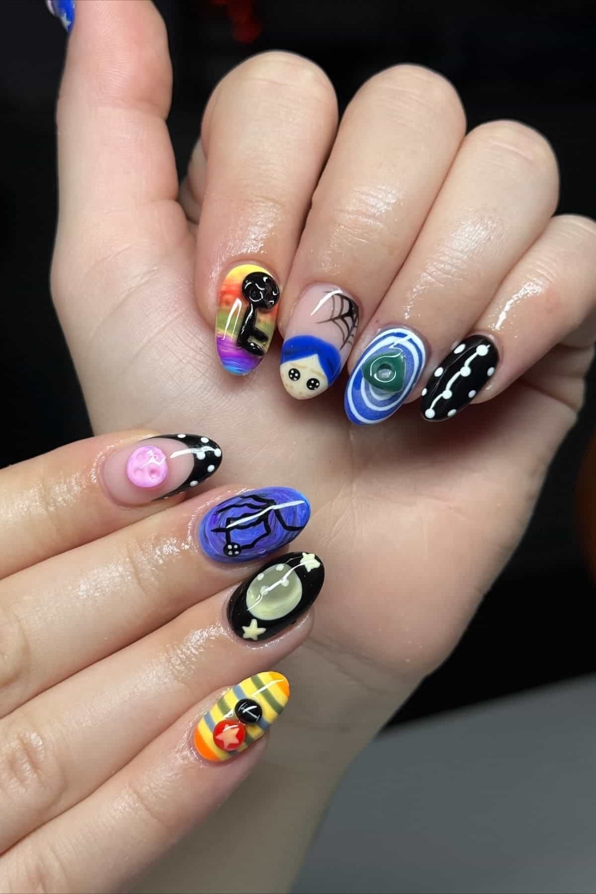 Hands with colorful, detailed nail art featuring cartoon faces, stars, swirls, a bat, smiley face, rainbow, spiderweb, and night sky designs on each fingernail.