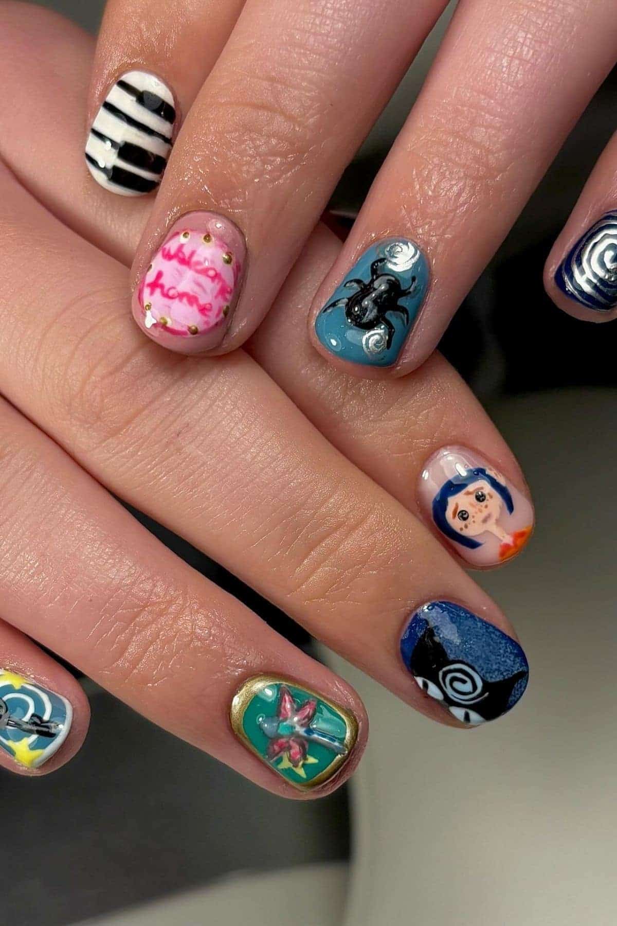 Close-up of hands with colorful nail art, including stripes, a blue-haired cartoon face, a black spider, flowers, a pink “Home” sign, and swirls on each fingernail.