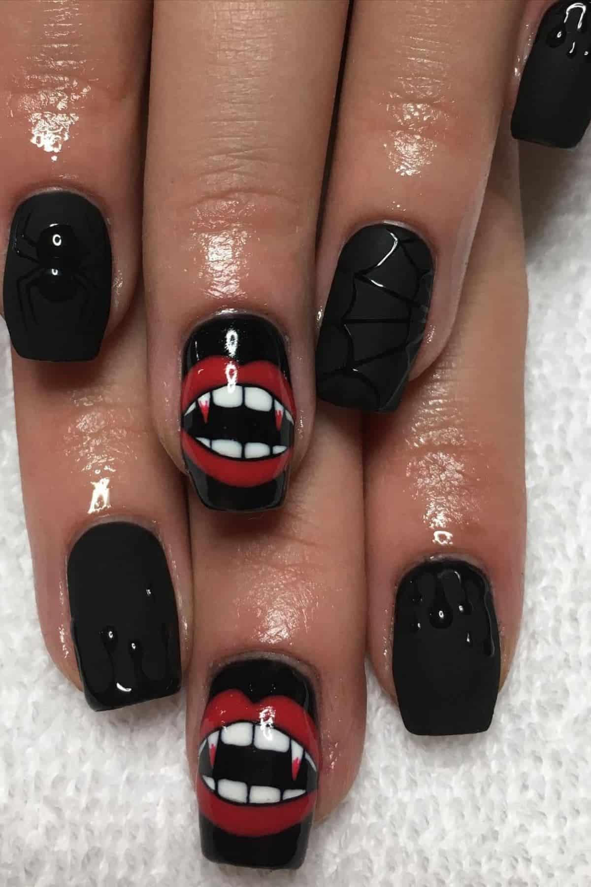 Black matte nails with Halloween designs: spiders, webs, and two nails featuring red lips with vampire fangs.