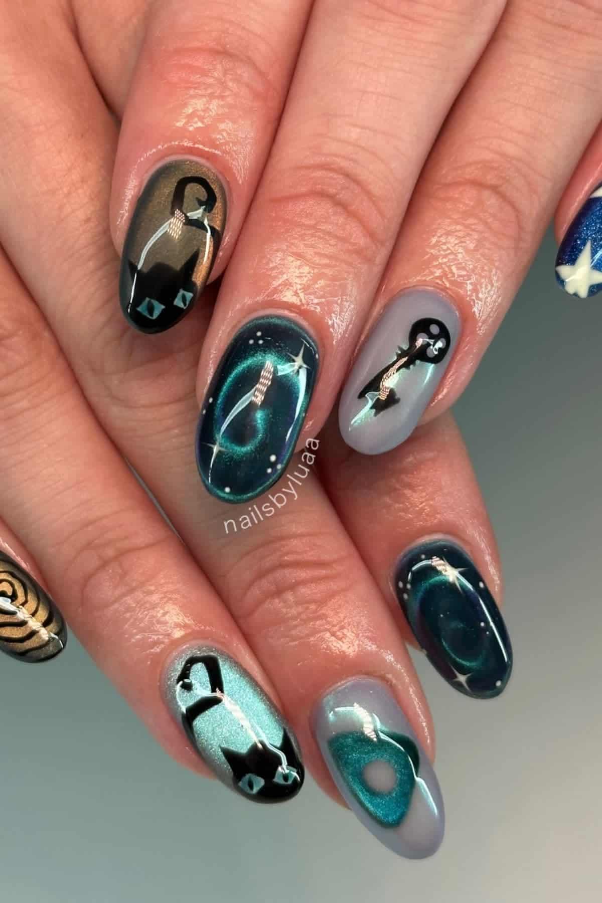 Close-up of hands with painted nails featuring aquarium and fish tank designs, including fish, aquatic plants, and water-themed backgrounds in blue, green, and black hues.