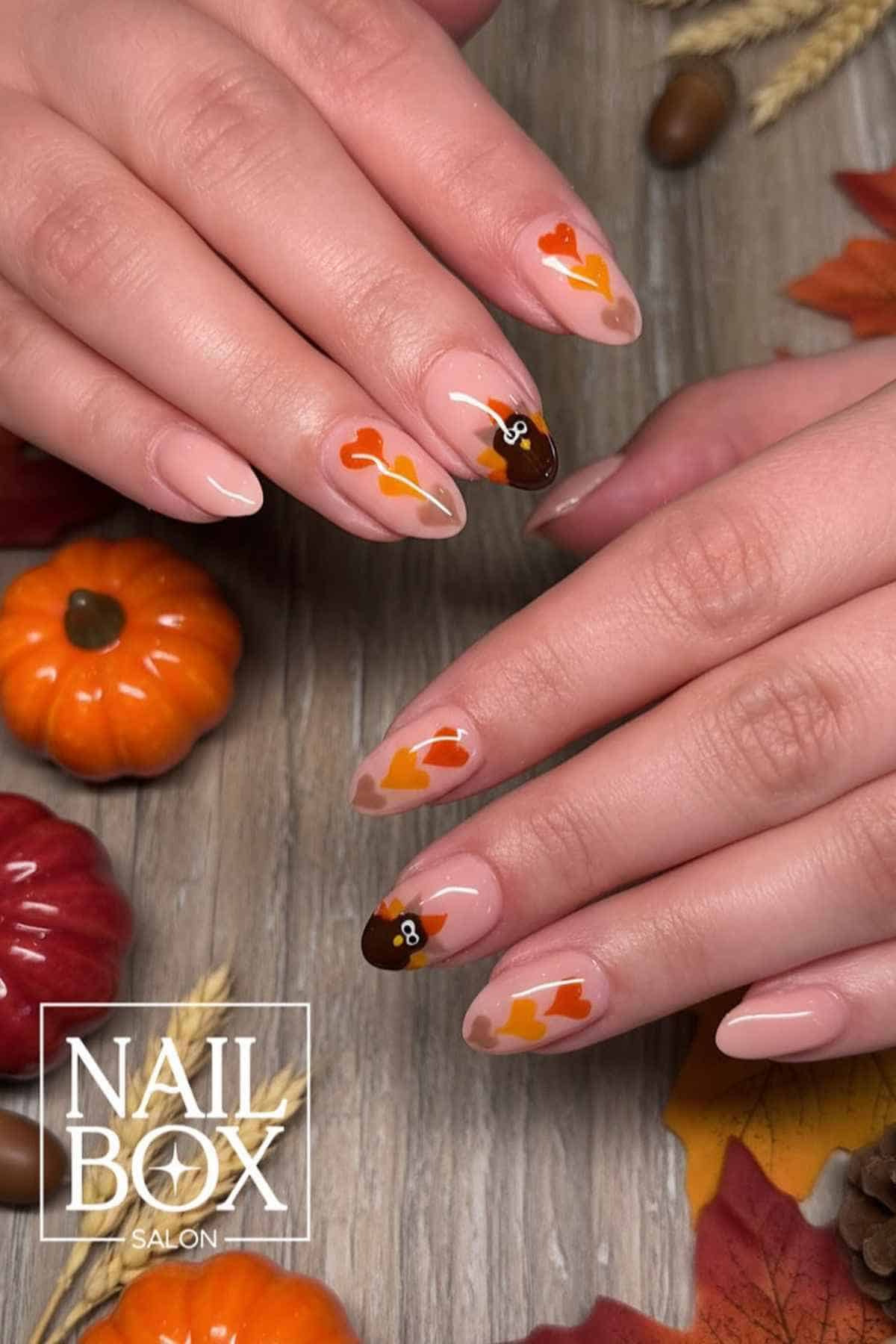 Manicured nails with a light pink base featuring painted turkey faces and orange heart accents.