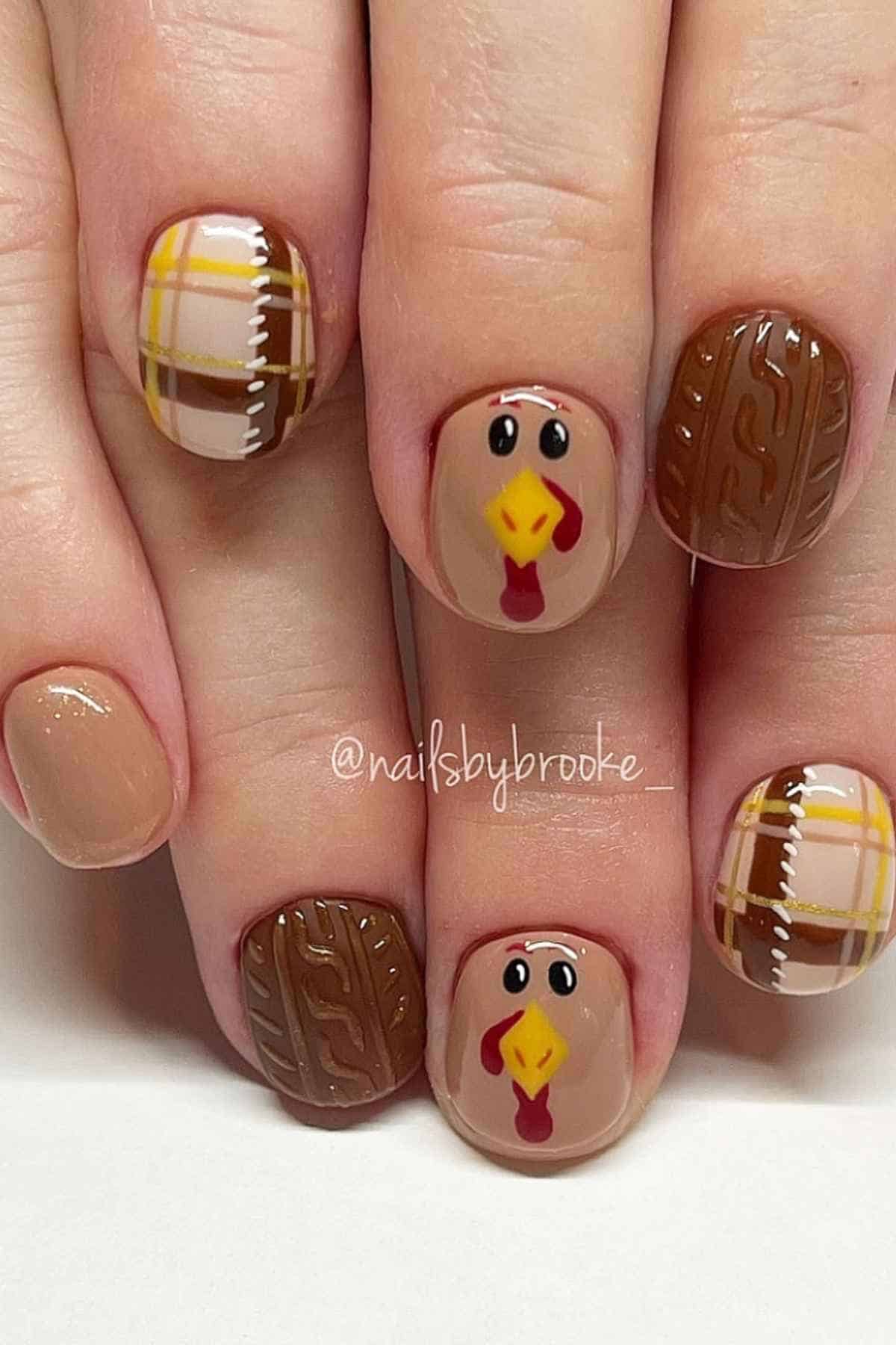 Fingernails painted with Thanksgiving-themed designs, including turkeys, brown cable-knit patterns, and yellow and brown plaid.