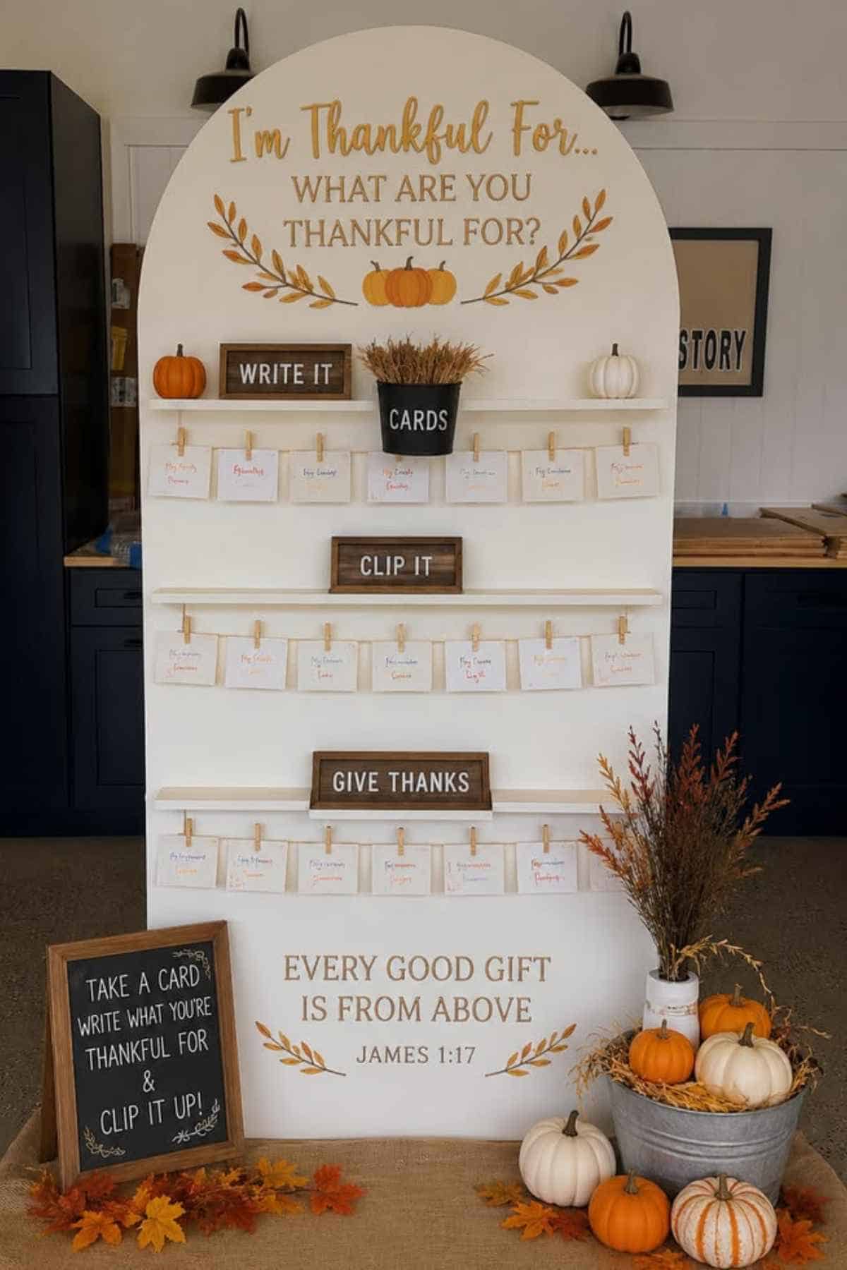 An arched display board titled “I’m Thankful For...” with clothespins to hold cards, surrounded by small pumpkins and signage with instructions.