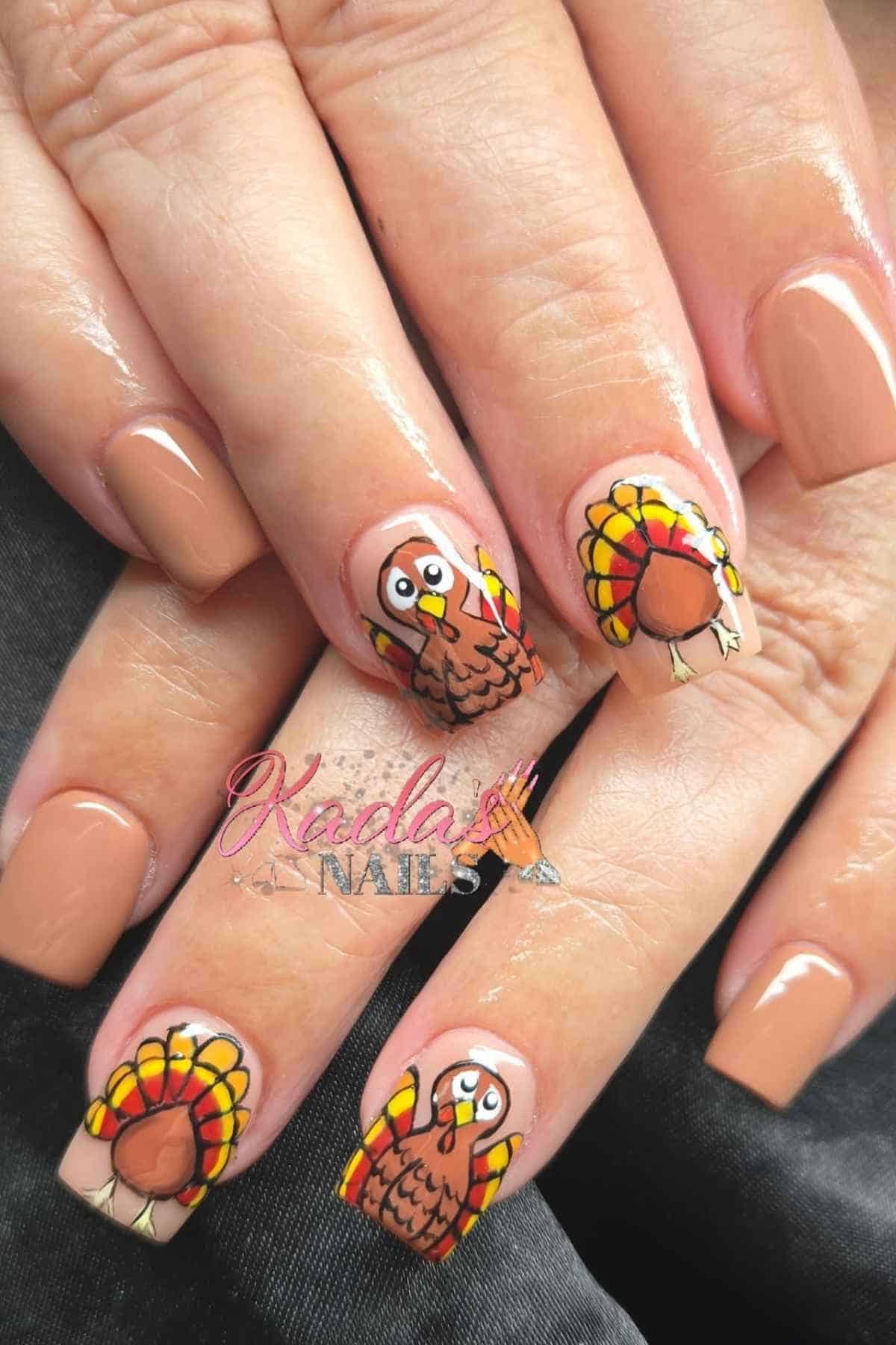 Manicured nails painted tan, with three nails featuring hand-painted cartoon turkeys.