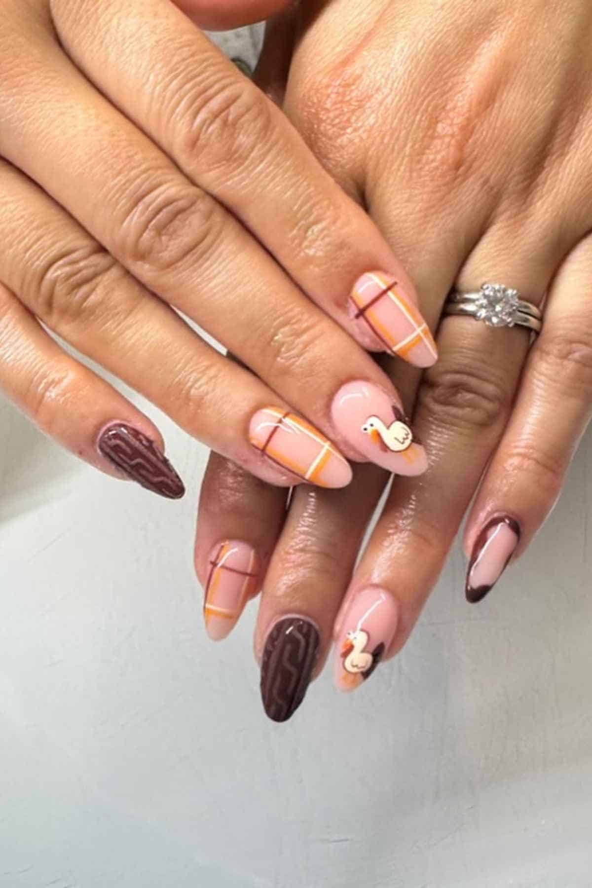 Manicured nails featuring a mix of light pink and dark brown polish, with plaid patterns, cable knit textures, and small turkey decals.