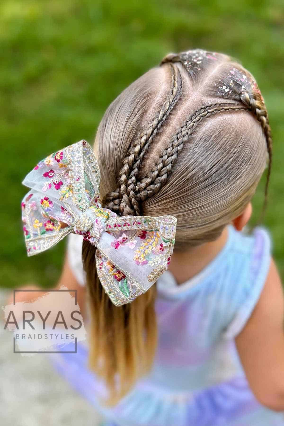 Child with three Dutch braids converging at the back of the head, secured with a large floral-patterned hair bow.
