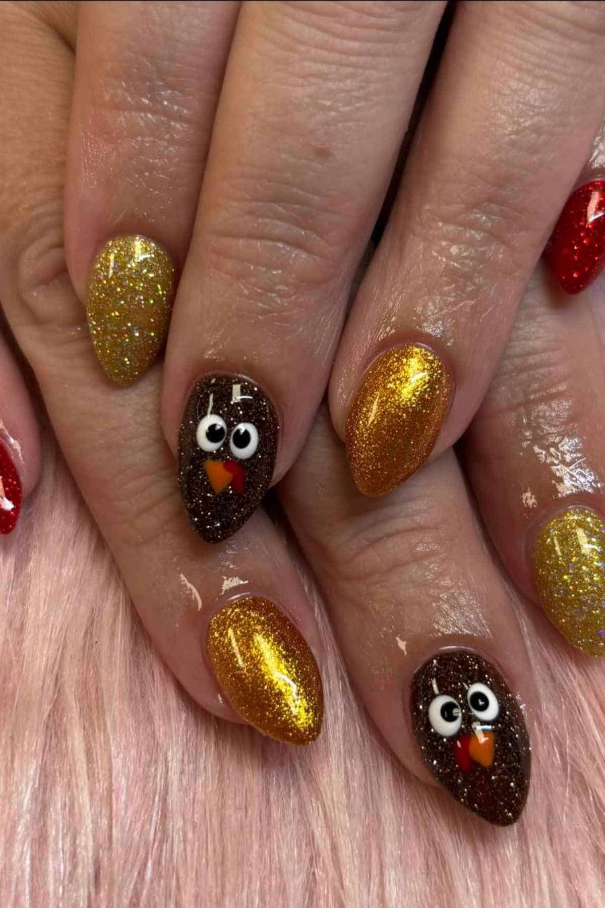 Manicured fingernails with gold glitter polish and two accent nails featuring painted turkey faces.
