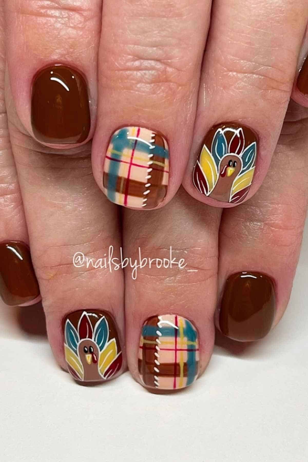 Manicure with solid brown nails, plaid accent nails, and hand-painted turkey designs.