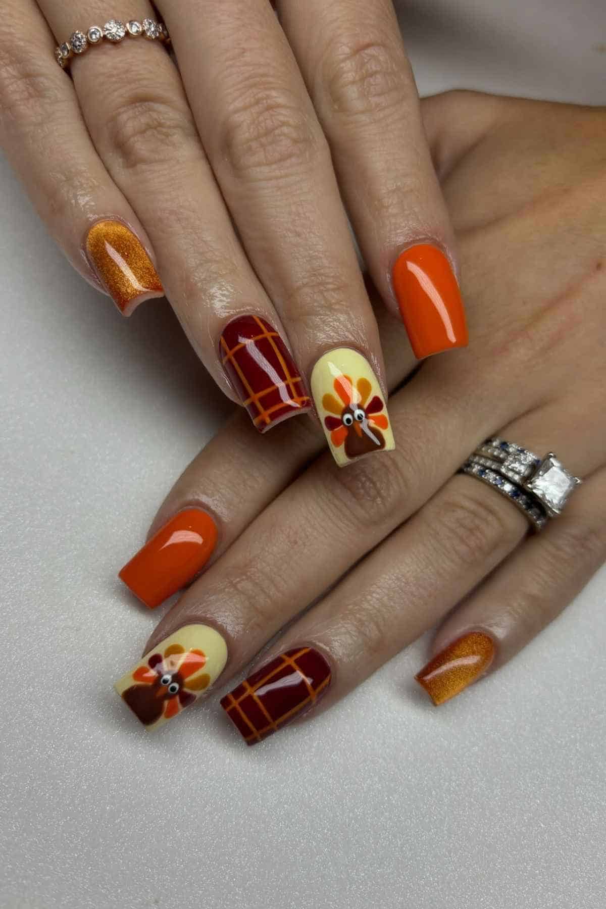 Square-shaped nails featuring Thanksgiving-themed nail art, including orange polish, a red plaid pattern, and a turkey design on a light yellow background.