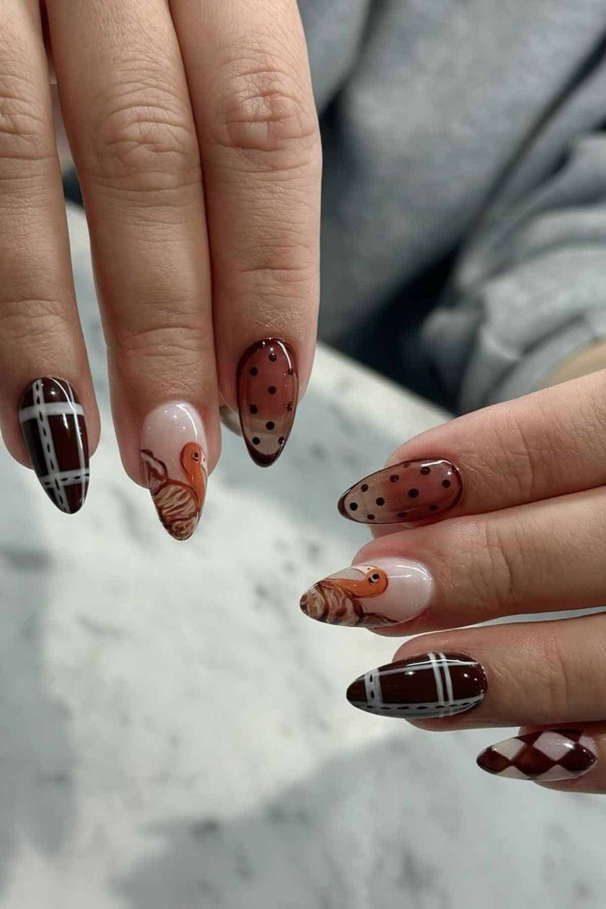 Manicured almond-shaped nails featuring Thanksgiving-themed art, including turkeys, brown polka dots, and plaid patterns.