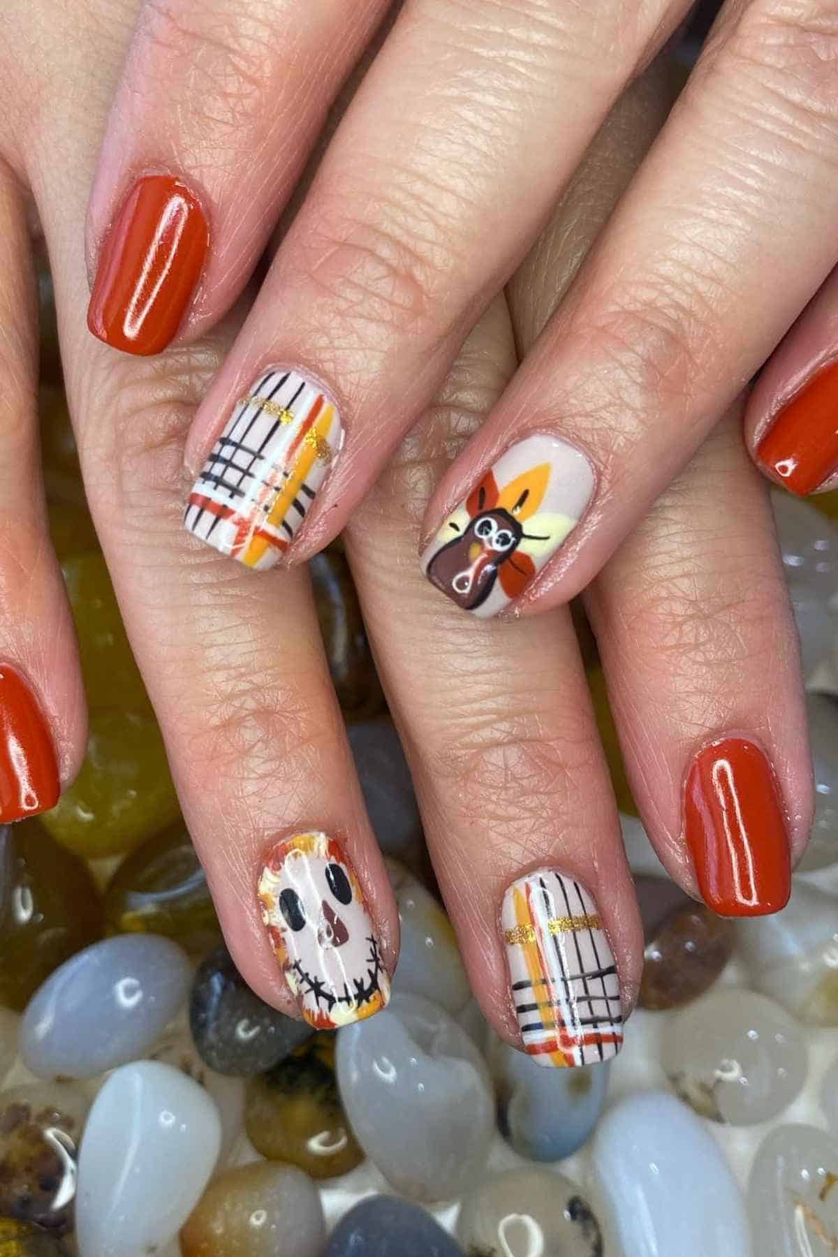 Manicured nails featuring a Thanksgiving theme with orange polish, plaid patterns, a turkey, and a Jack Skellington face.