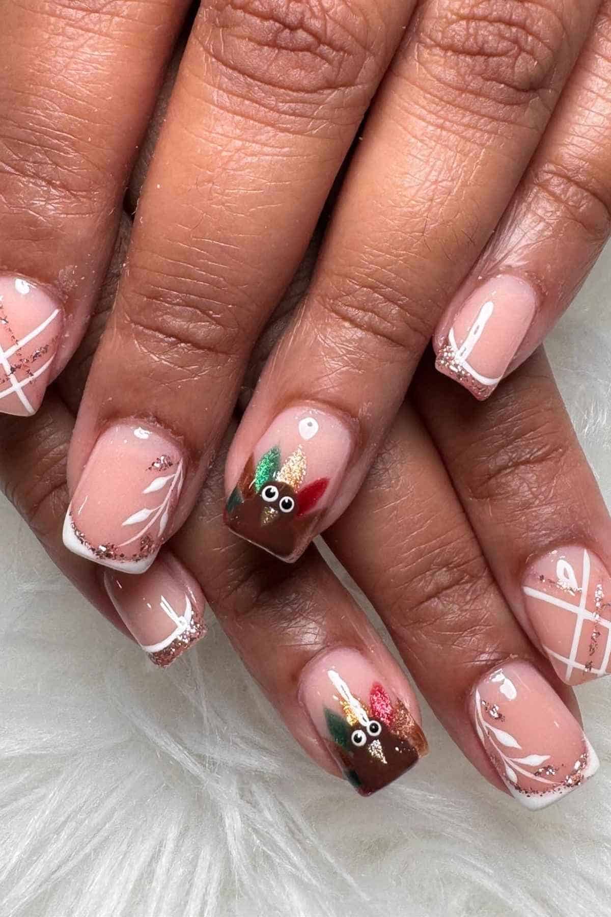 Manicured nails featuring a pink base with white line art, glitter accents, and two nails decorated with painted turkey faces.