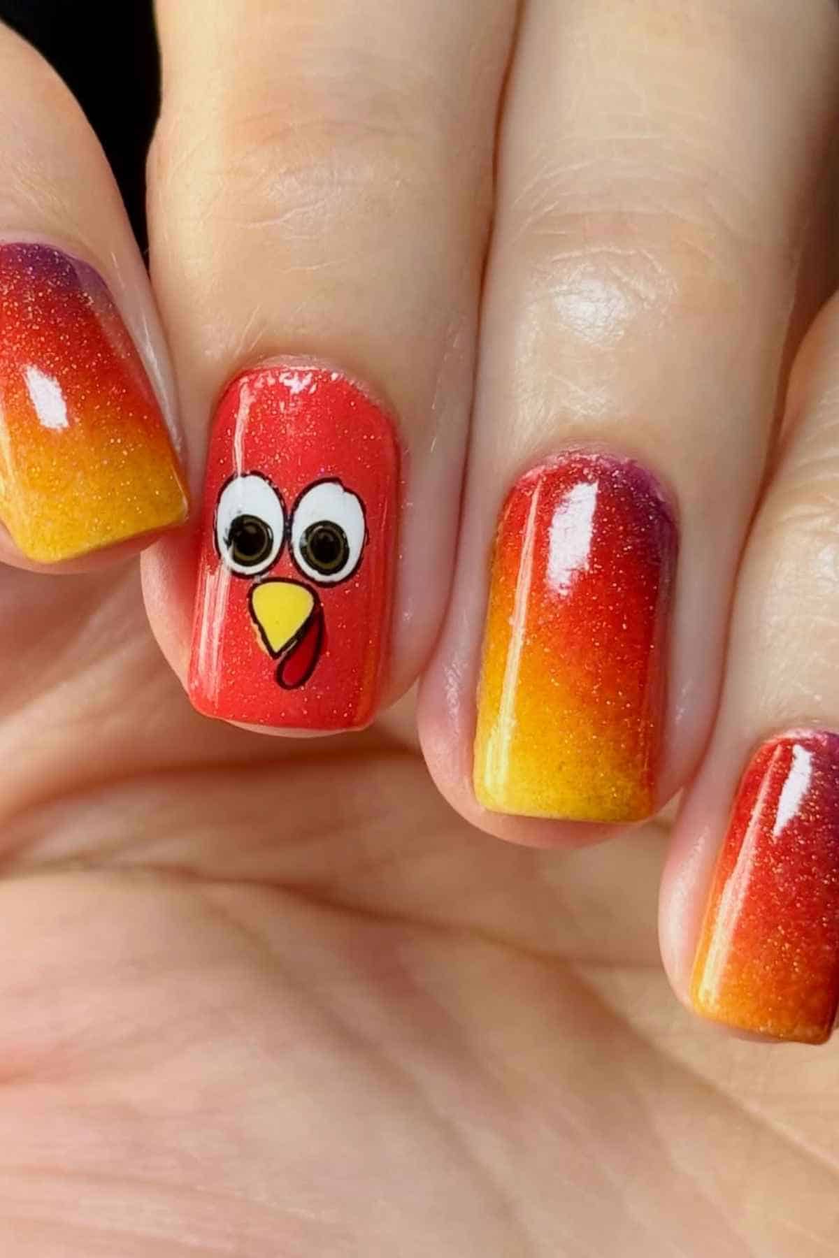 Fingernails painted with a red-to-yellow gradient, featuring a turkey face painted on the middle fingernail.