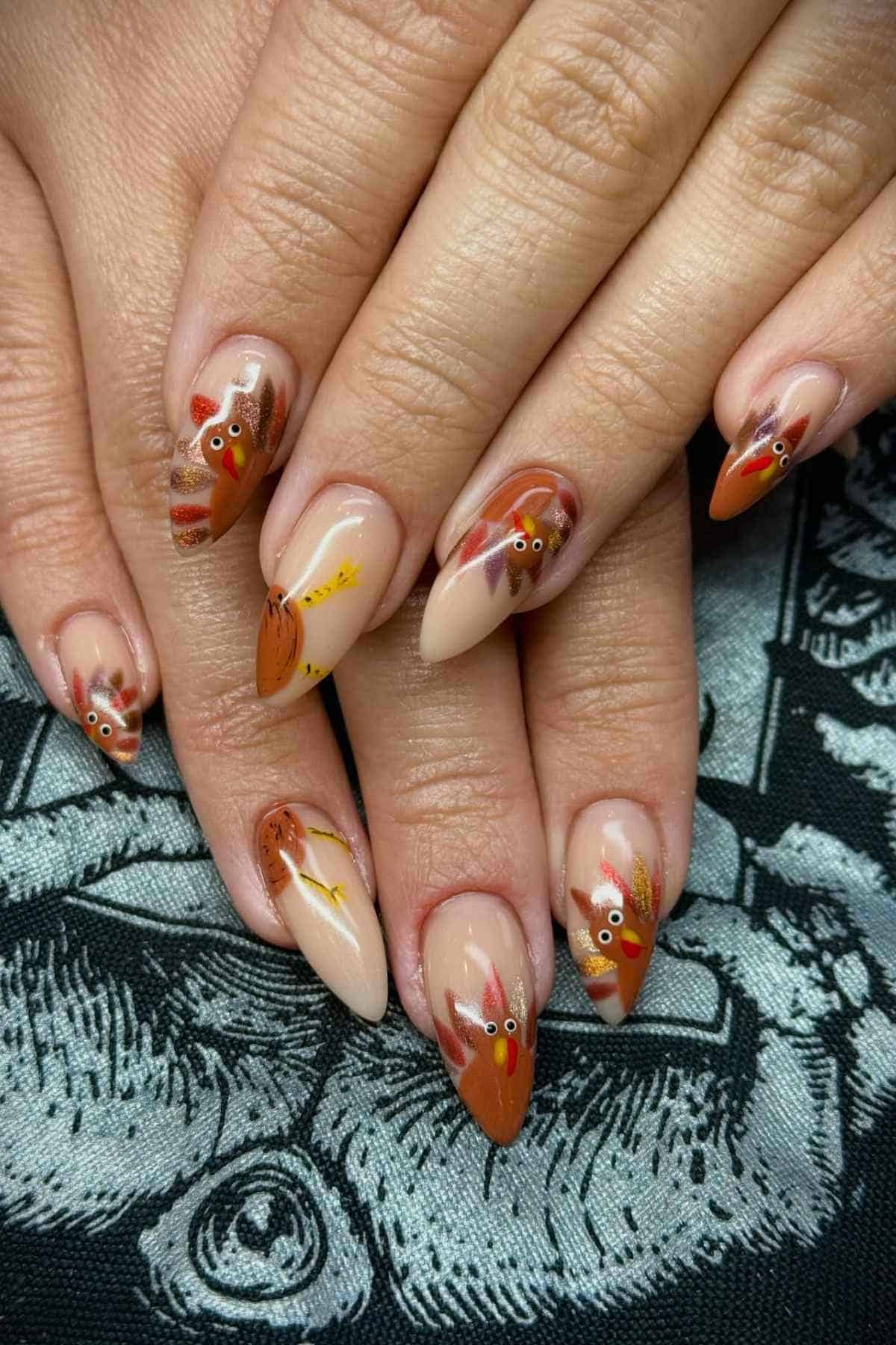 Almond-shaped fingernails featuring hand-painted turkey designs with gold glitter accents.