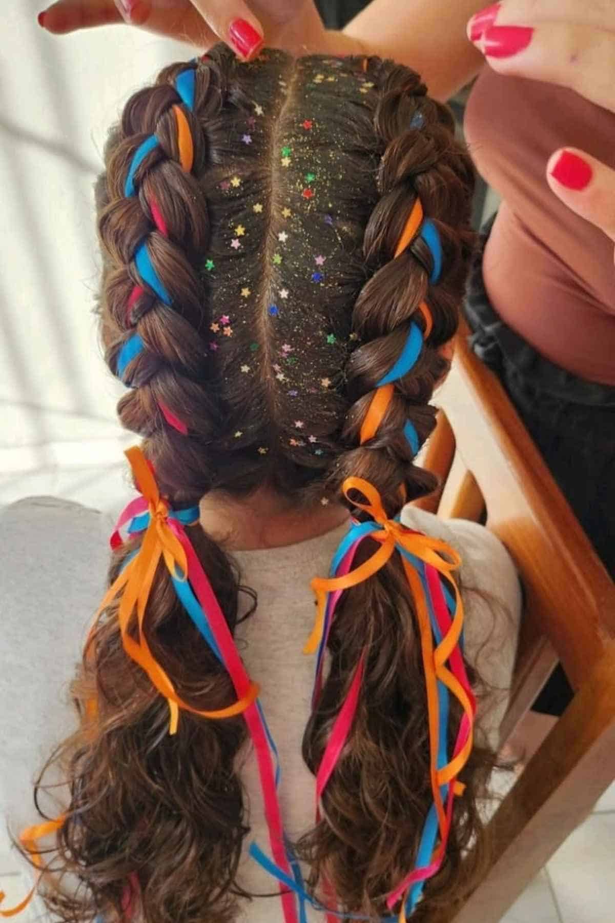 Two French braids styled with colorful ribbons and star-shaped glitter along the center part.