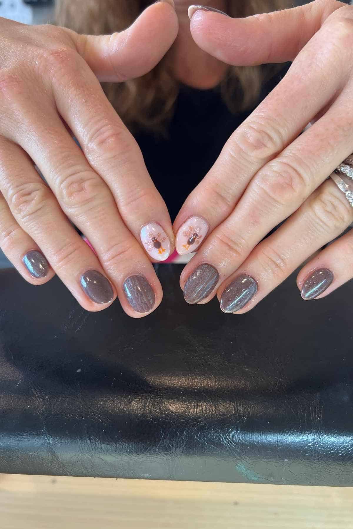 Hands showing a manicure with brown glitter polish and two accent nails featuring turkey decals.